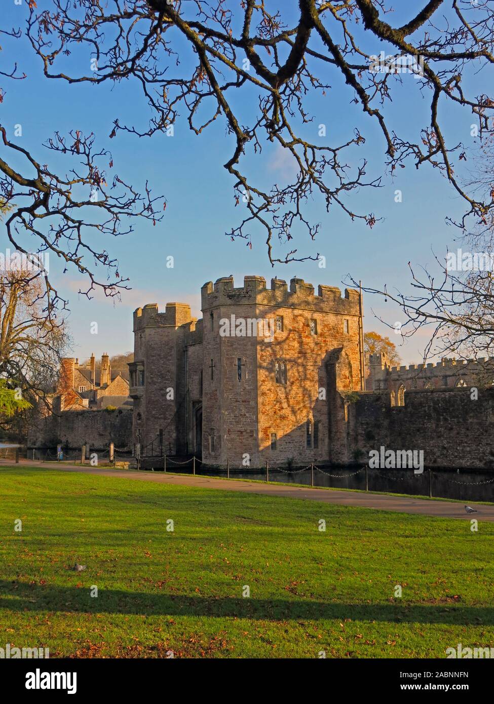 Una debole inverno il sole splende sul gatehouse oltre il fossato del Palazzo del Vescovo in pozzetti, Somerset, Inghilterra, Regno Unito Foto Stock