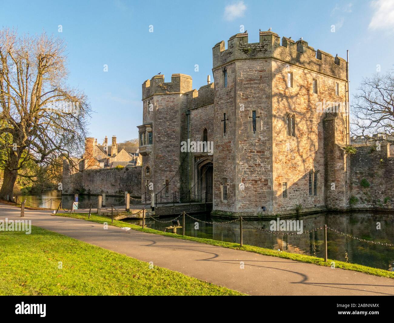 Una debole inverno il sole splende sul gatehouse oltre il fossato del Palazzo del Vescovo in pozzetti, Somerset, Inghilterra, Regno Unito Foto Stock