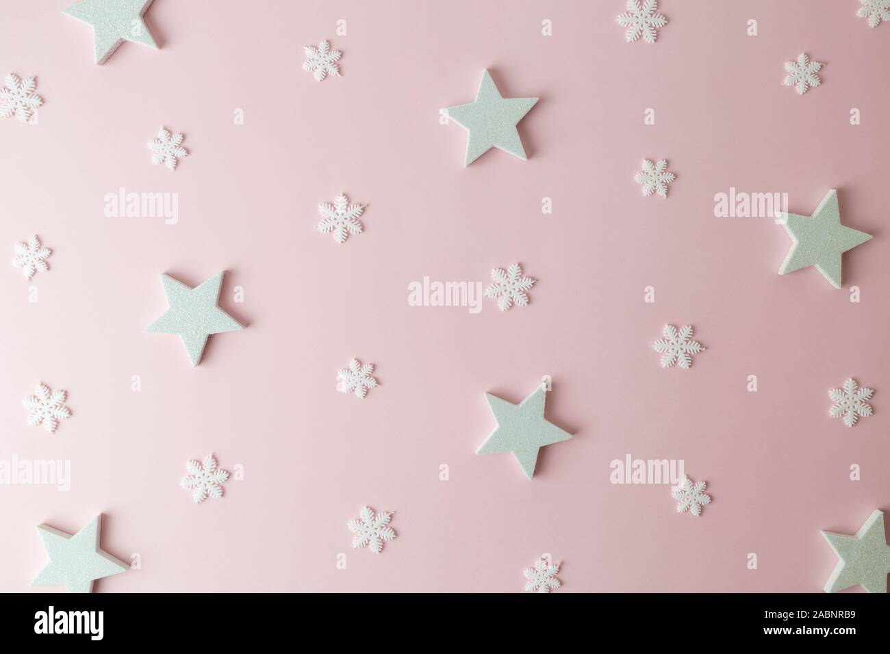 Modello realizzato di stelle bianche e i fiocchi di neve sul rosa pastello background creativo minima per le vacanze di Natale e il concetto d'inverno. Foto Stock