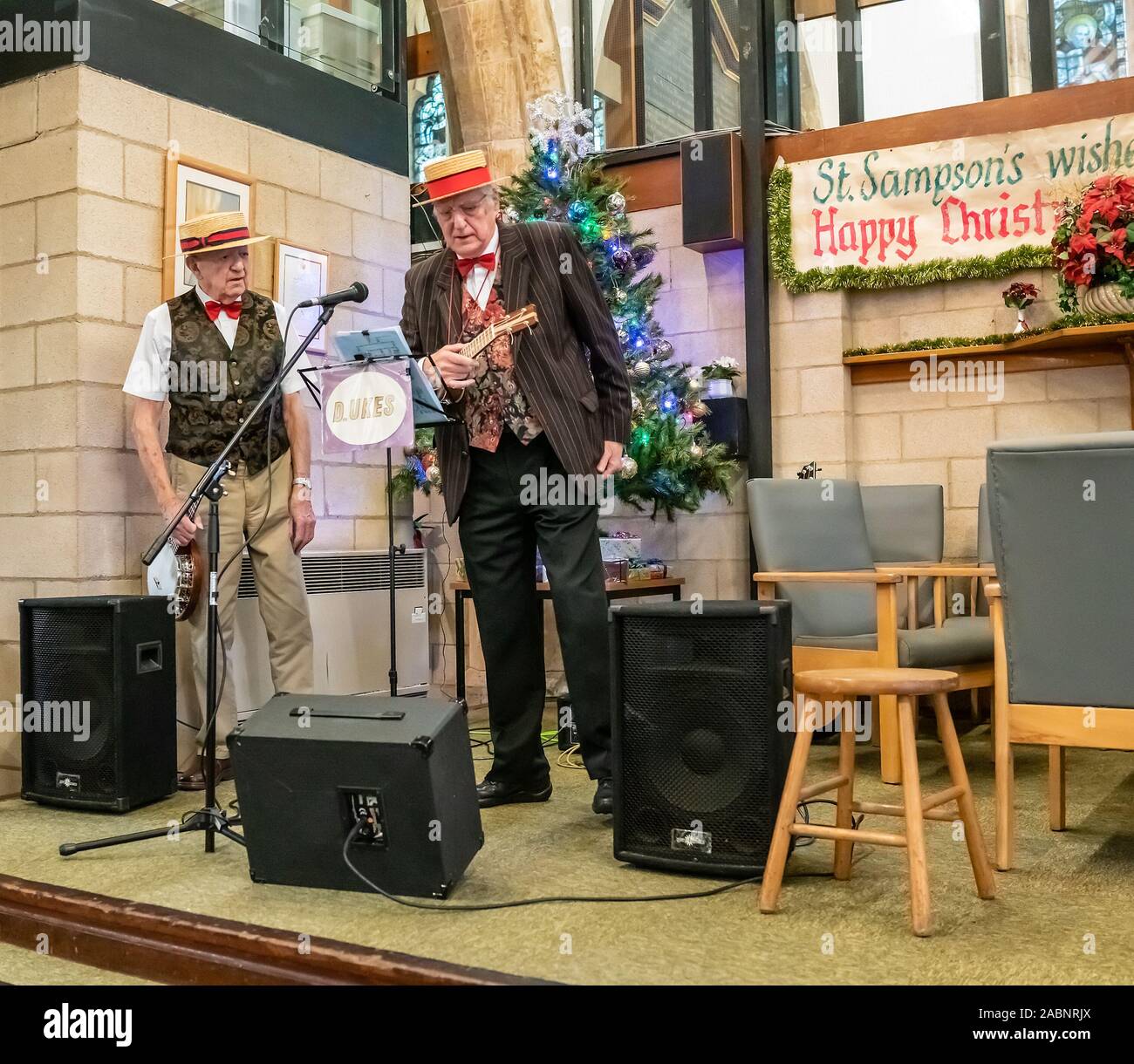 Due anziani signori giocando l'ukulele ad una festa di Natale il caffè la mattina in St Sampson Chiesa, York Foto Stock Due anziani signori giocando l'ukulele ad una festa di Natale il caffè la mattina in St Sampson Chiesa, York Foto Stock