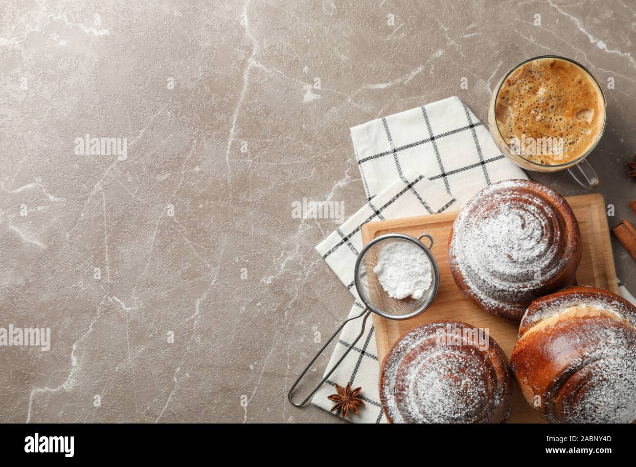 Gustosa cinnamon roll con ingredienti, caffè su sfondo marrone, spazio per il testo. Vista superiore Foto Stock