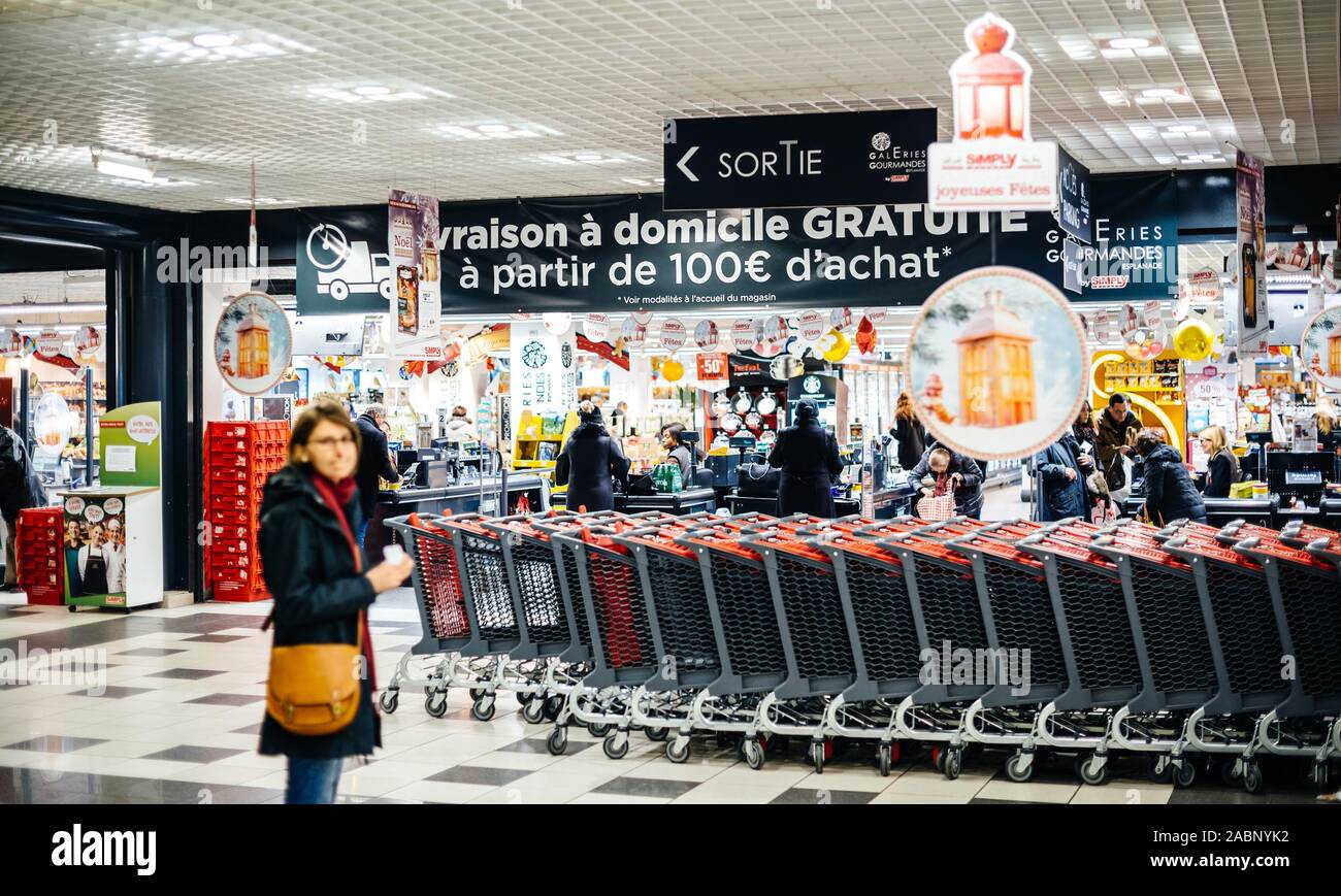 Strasburgo, Francia - Dic 21, 2016: silhouette di donna in attesa vicino i carrelli di shopping nella grande francese supermercato Auchan Foto Stock