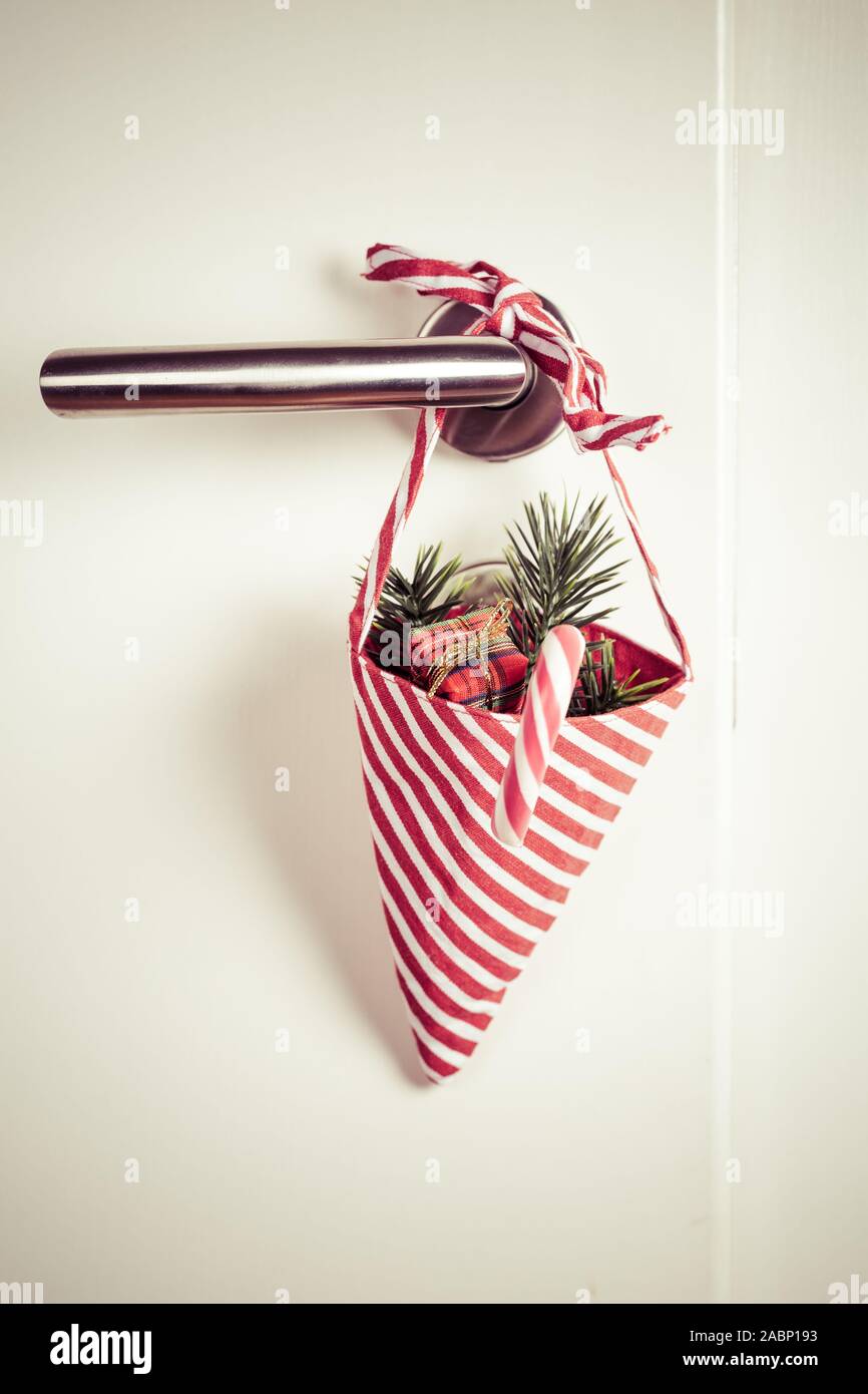 Piccolo sacchetto di Natale con le filiali e candy cane appeso alla maniglia della porta in stile vintage Foto Stock