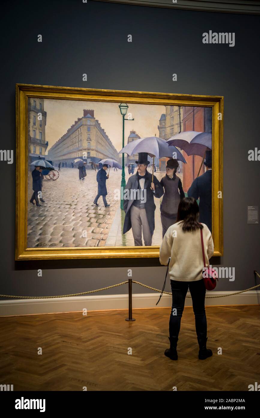 Visitatore guardando Gustave Caillebotte dipinto 'Paris Street; Rainy day", 1877, l'Art Institute of Chicago, Chicago, Illinois, Stati Uniti d'America Foto Stock