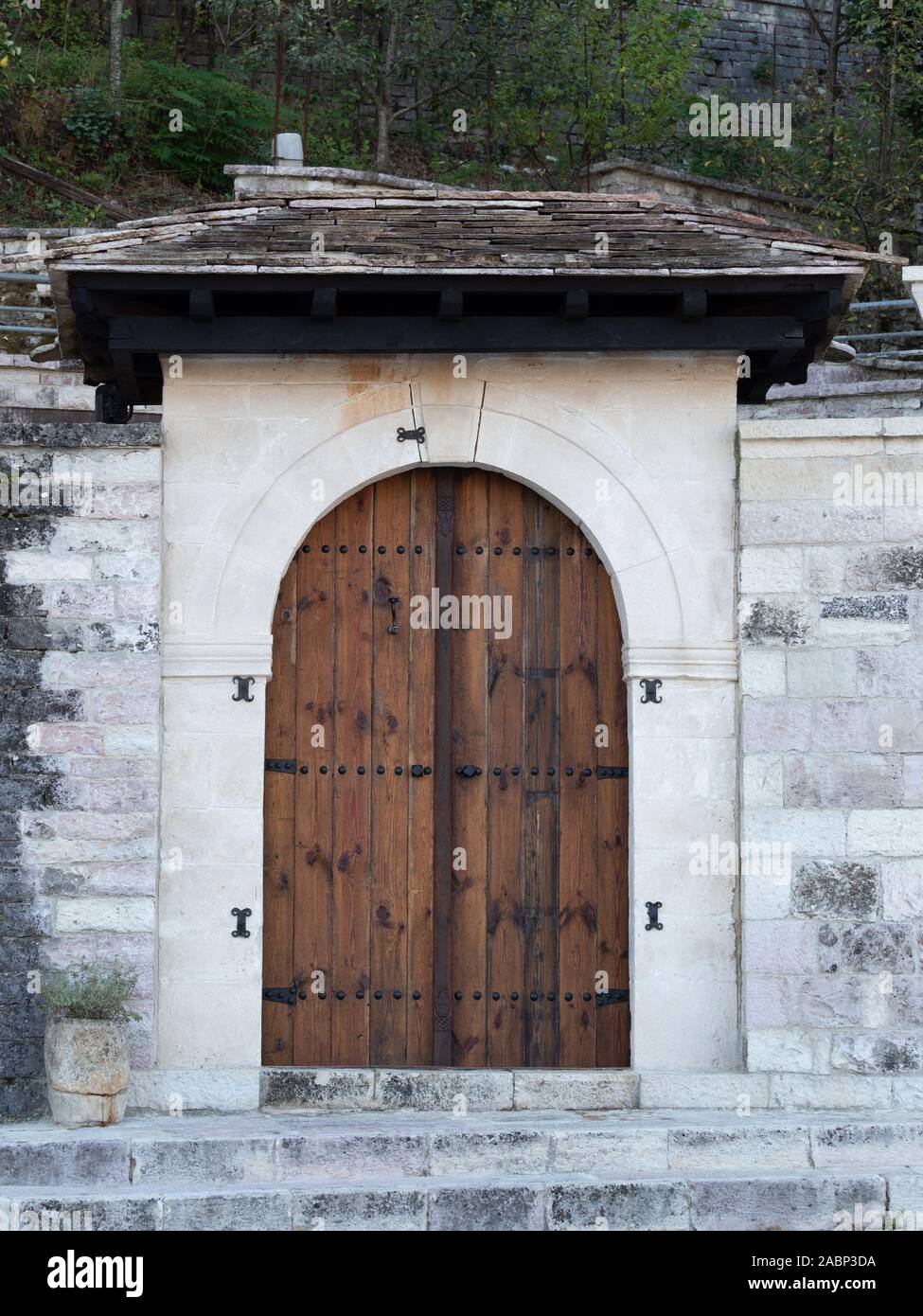 Il bianco e il grigio della pietra con parete ad arco in legno porta doppia entrata e tetto in ardesia. Foto Stock