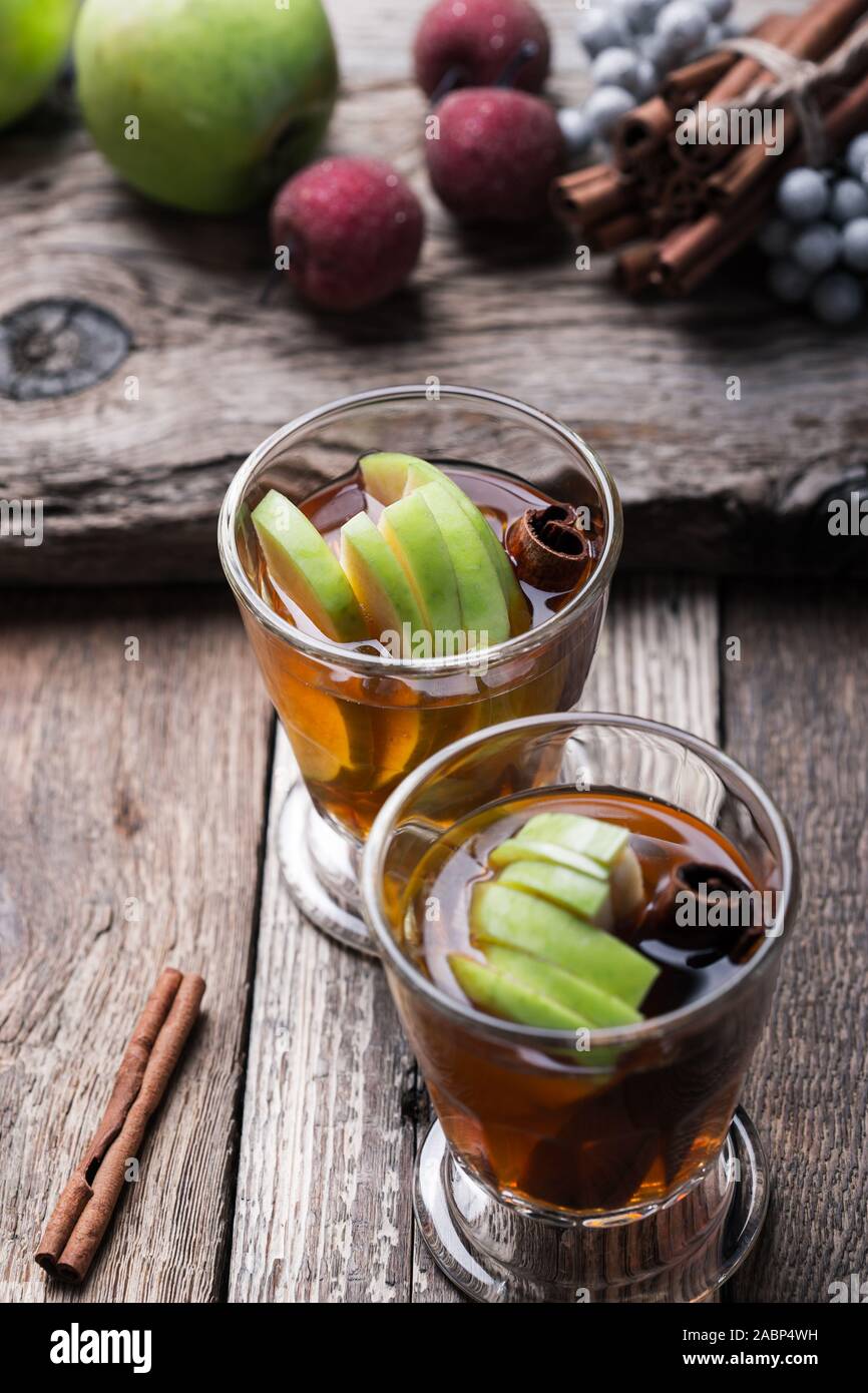 Natale tradizionale riscaldamento invernale cocktail, rimuginassero sidro di mela bevanda con bastoncini di cannella, bevande in bicchieri rustico sul tavolo di legno, close up Foto Stock
