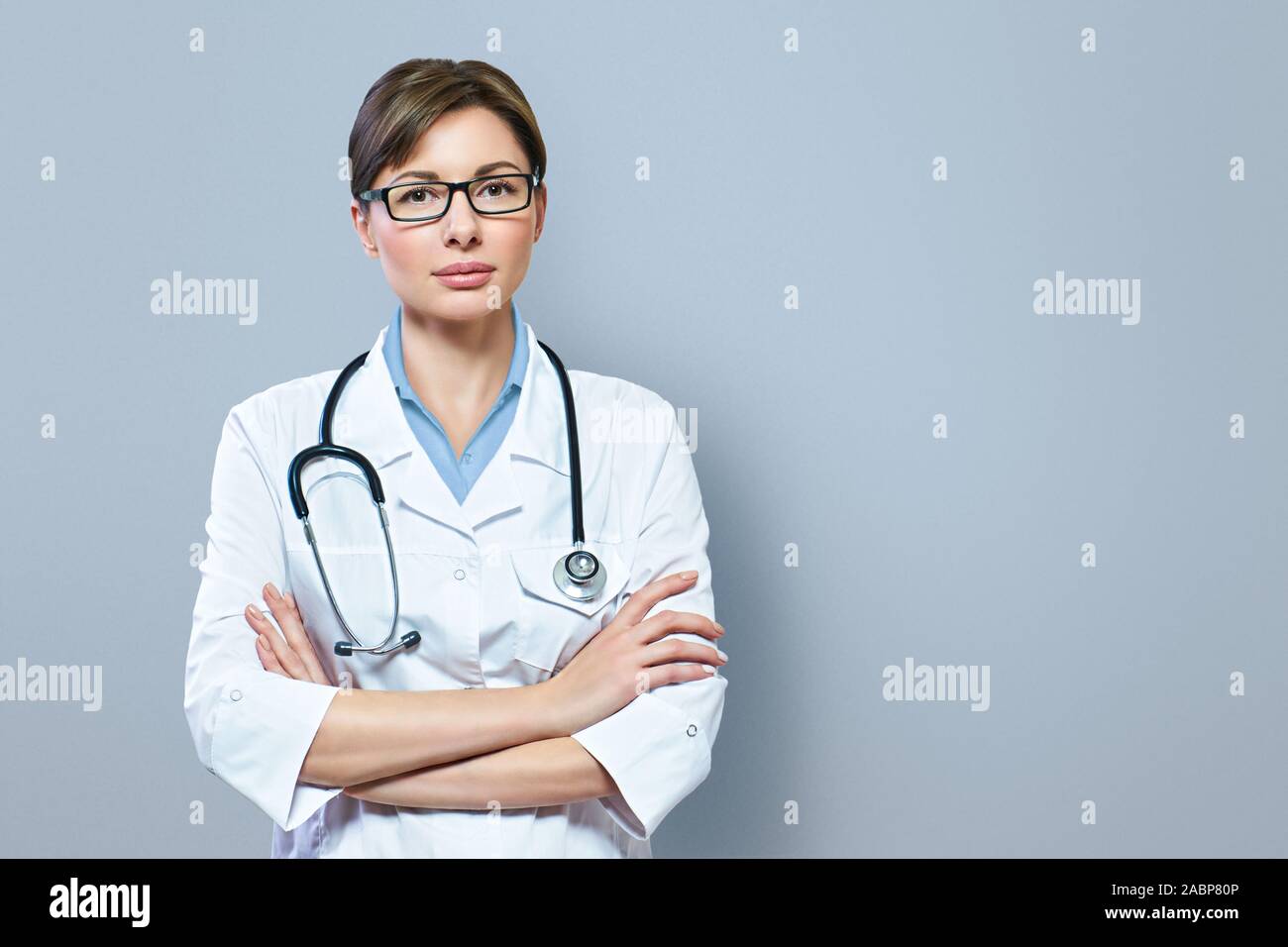 Ritratto di grave medico con stetoscopio guardando la fotocamera.medico medico medico donna blu su sfondo clinica Foto Stock