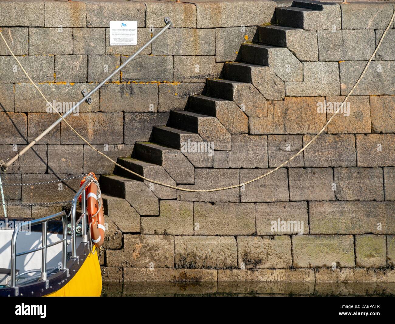 Grande incastro esagonale irregolare dei blocchi di granito fasi di formatura della parete di Scalasaig molo del porto, Isola di Colonsay, Scotland, Regno Unito Foto Stock