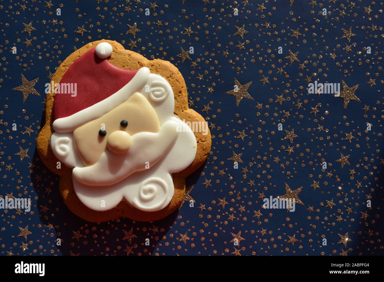 Gingerbread cookie nella forma di Babbo Natale su uno sfondo blu con stelle d'oro Foto Stock