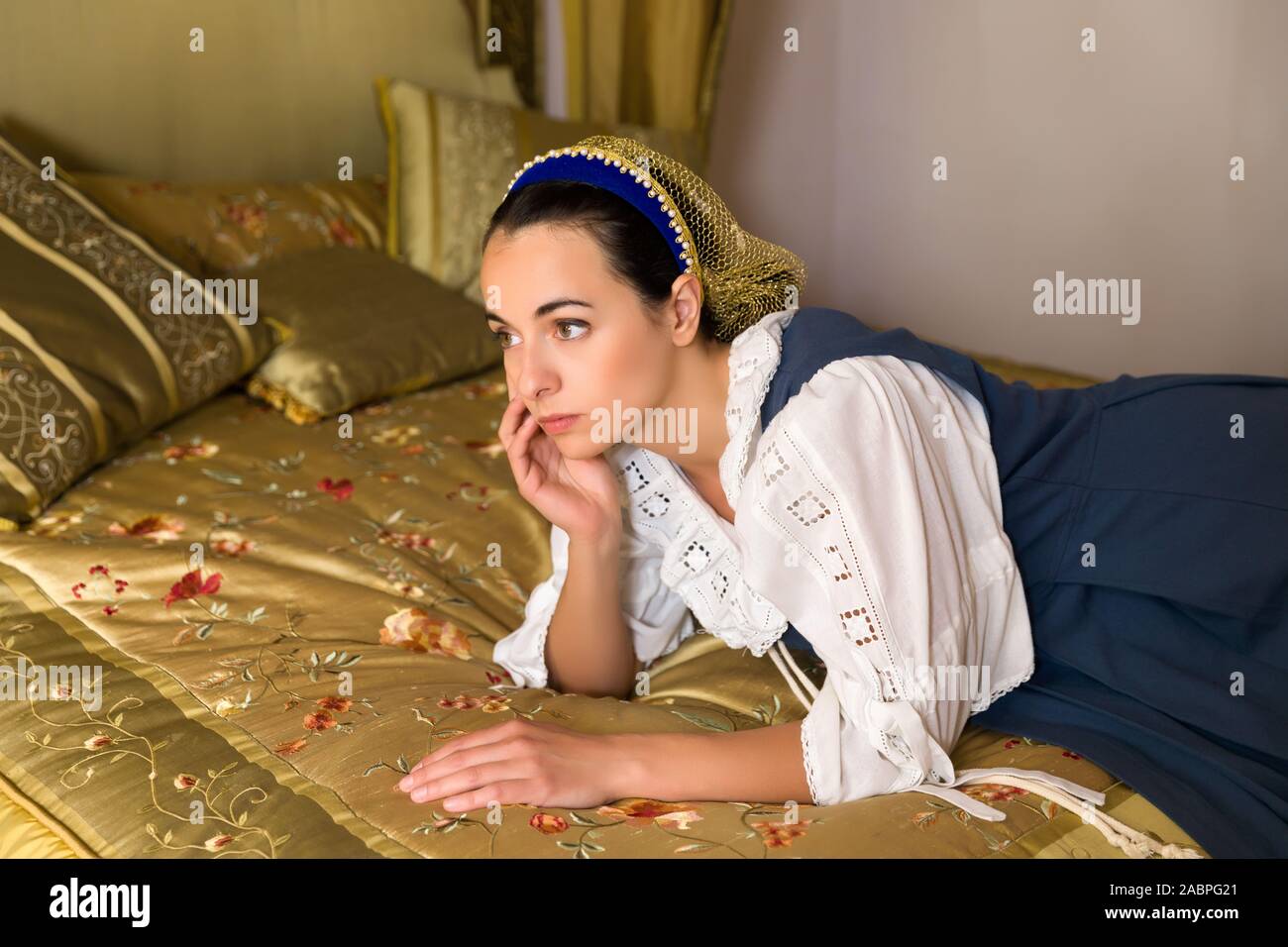 Maestro olandese style ritratto di una giovane e bella donna in autentico costume rinascimentale giacente su un lusso antico letto a baldacchino in una camera da letto d'oro di un Foto Stock