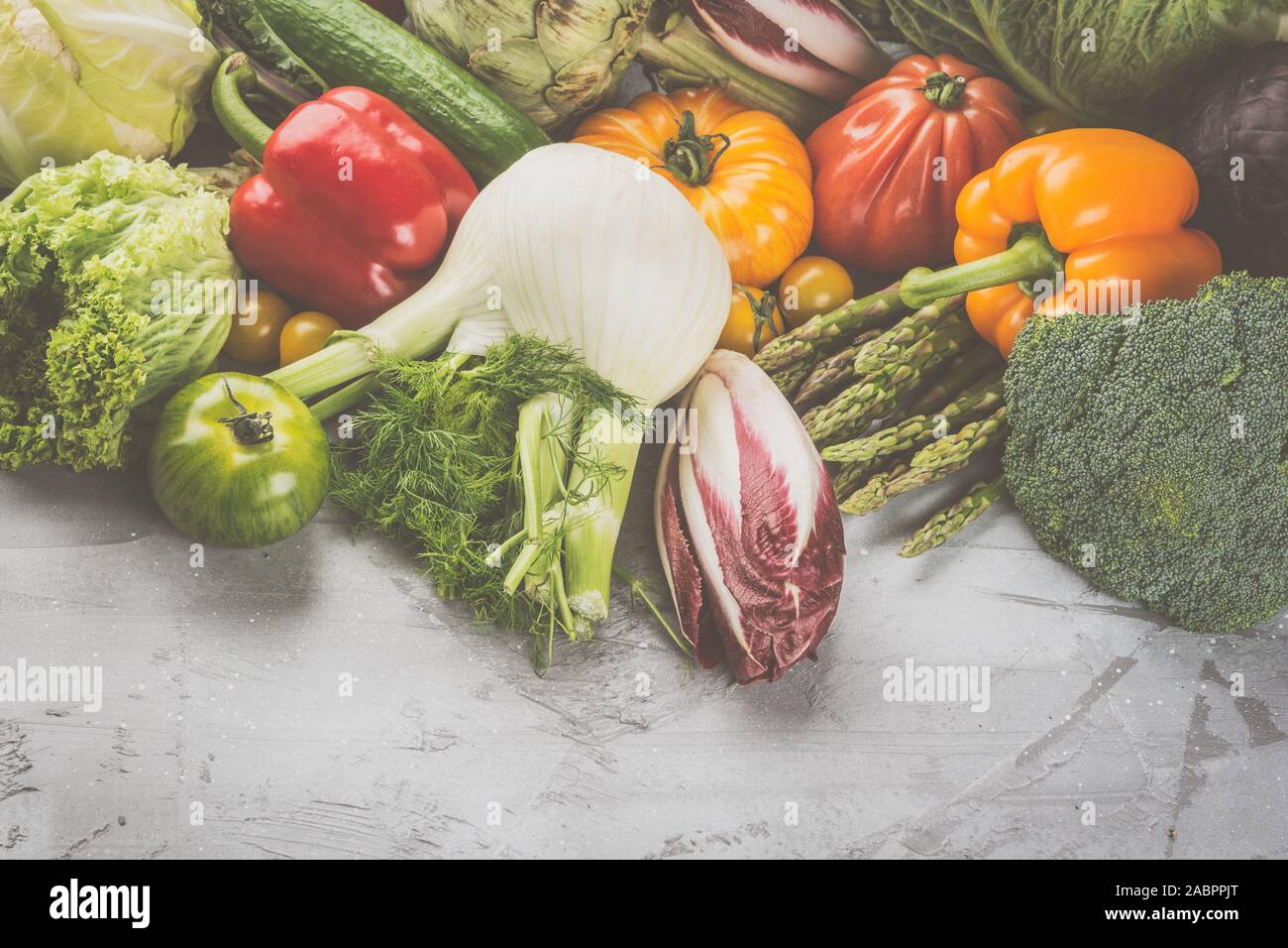 Fresche verdure crude sul cemento grigio Sfondo, vista dall'alto, spazio copia, tonica, il fuoco selettivo Foto Stock