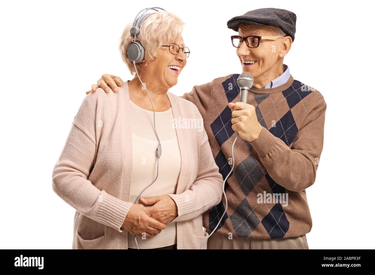 Uomo anziano cantando su un microfono per una donna anziana con cuffie isolato su sfondo bianco Foto Stock