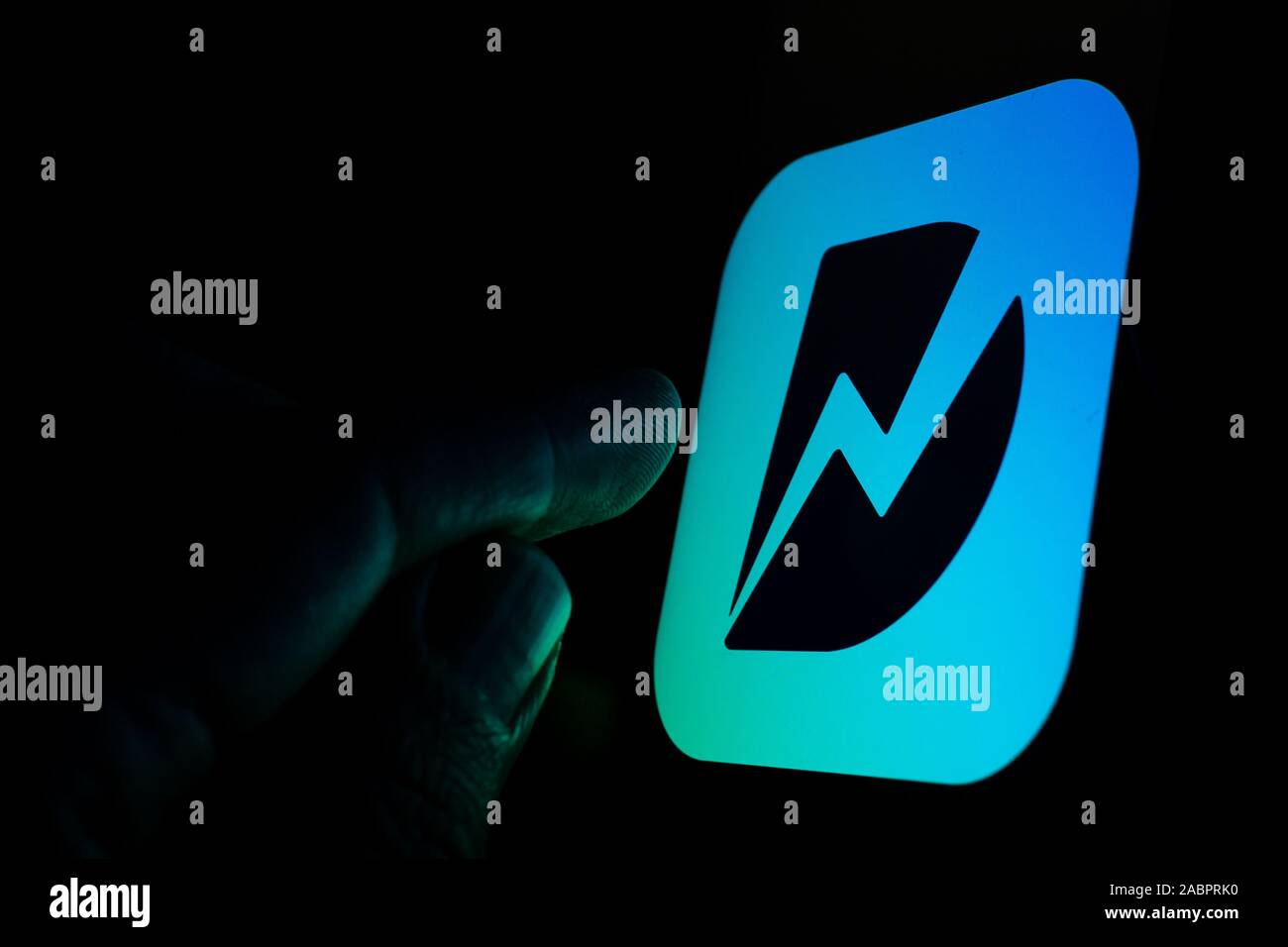 Dunzo consegna logo app incandescente sullo schermo in una stanza buia e puntare il dito in corrispondenza di essa. Messa a fuoco selettiva. Il focus principale è sul logo. Foto Stock