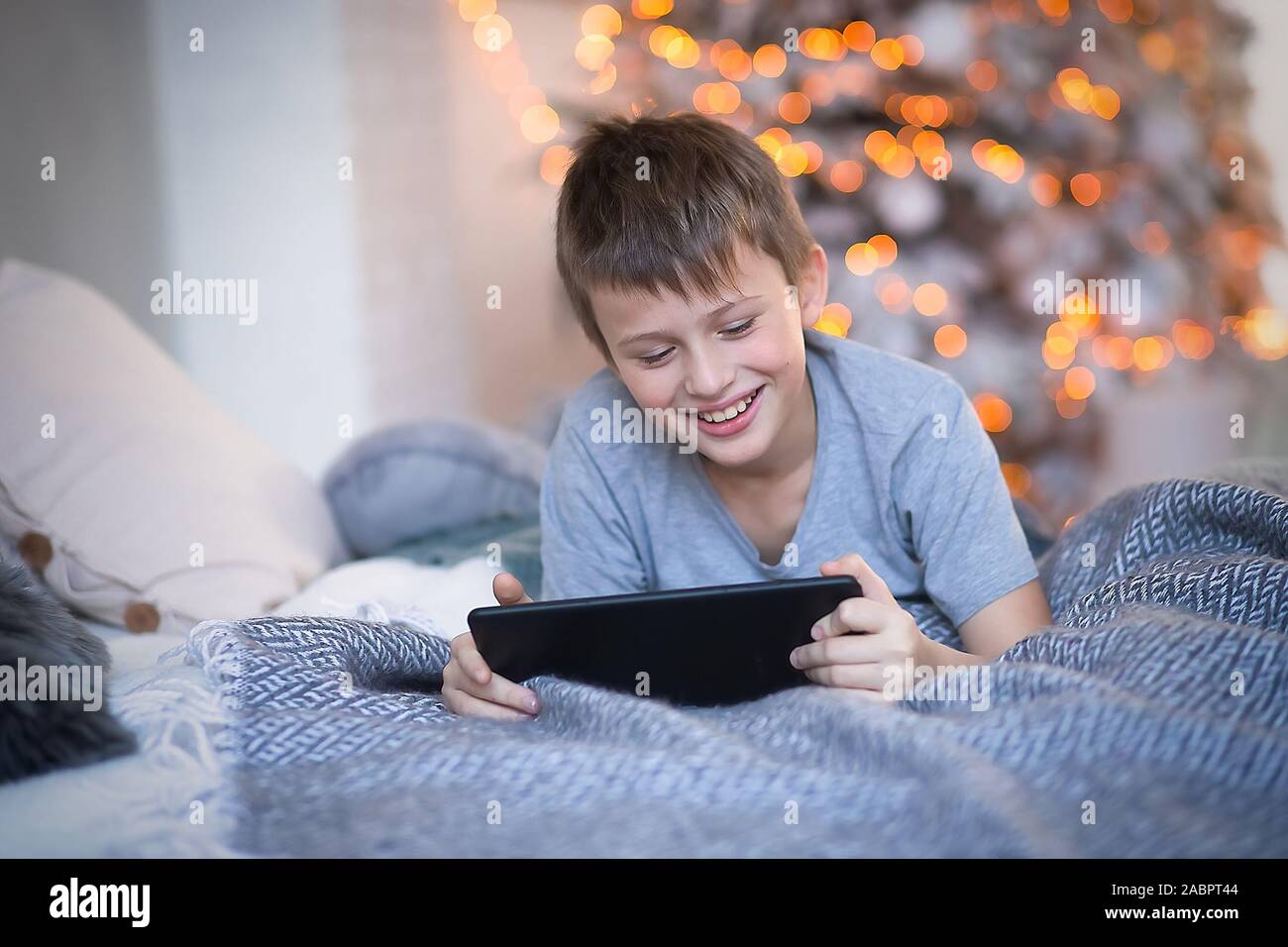 Bambino ride allegramente mentre guardando lo schermo tablet. boy ha vinto il gioco online. bambino utilizza gadget in vacanza prima di Natale. Foto Stock