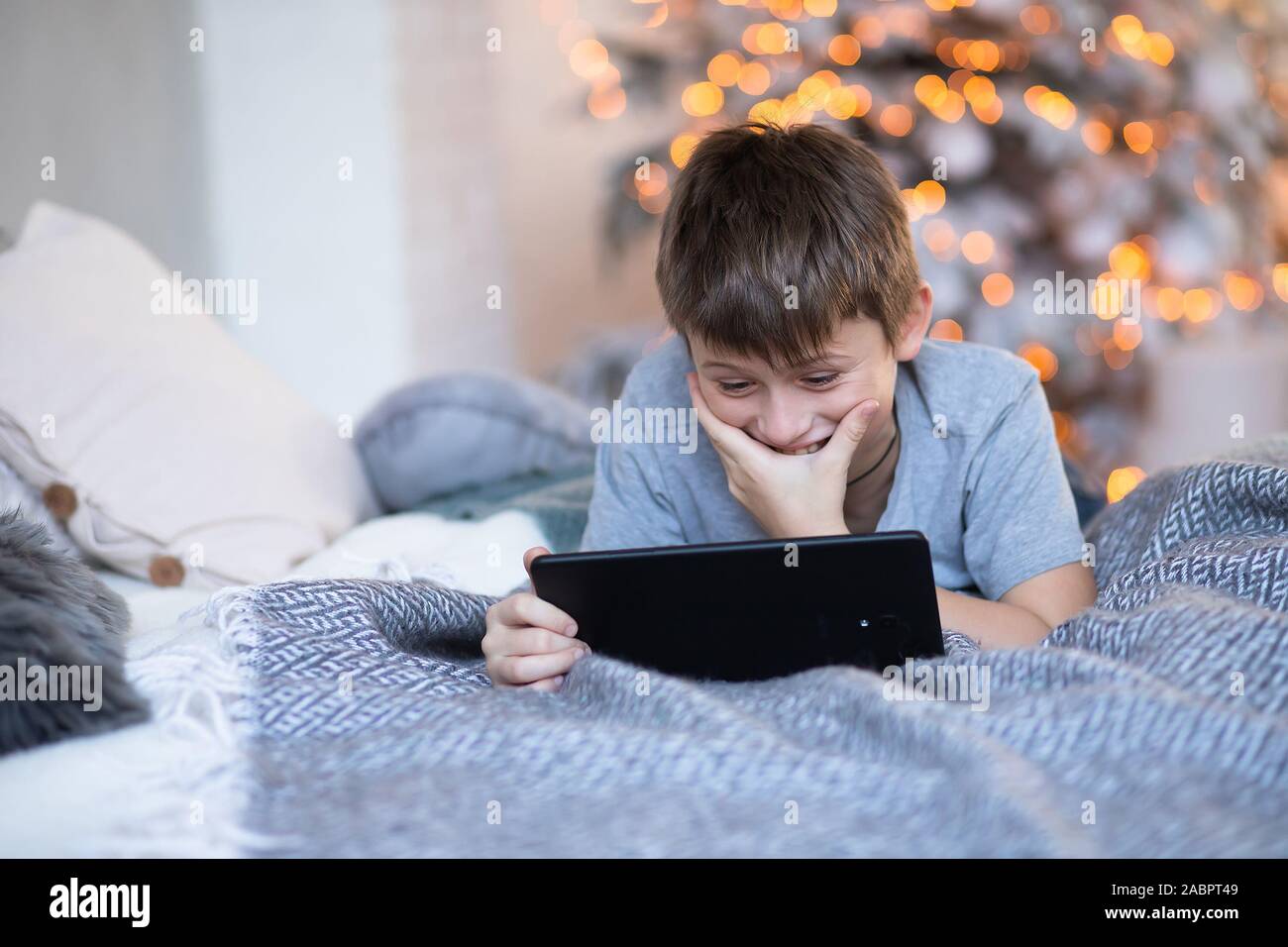 Bambino ride allegramente mentre guardando lo schermo tablet. boy ha vinto il gioco online. bambino utilizza gadget in vacanza prima di Natale. Foto Stock