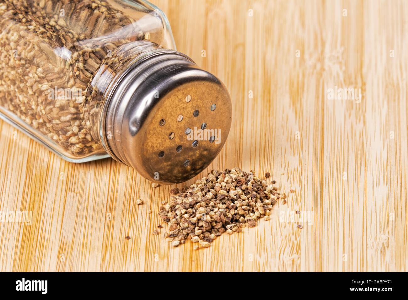 Pepaiola di pepe nero macinato su un sfondo di legno Foto Stock