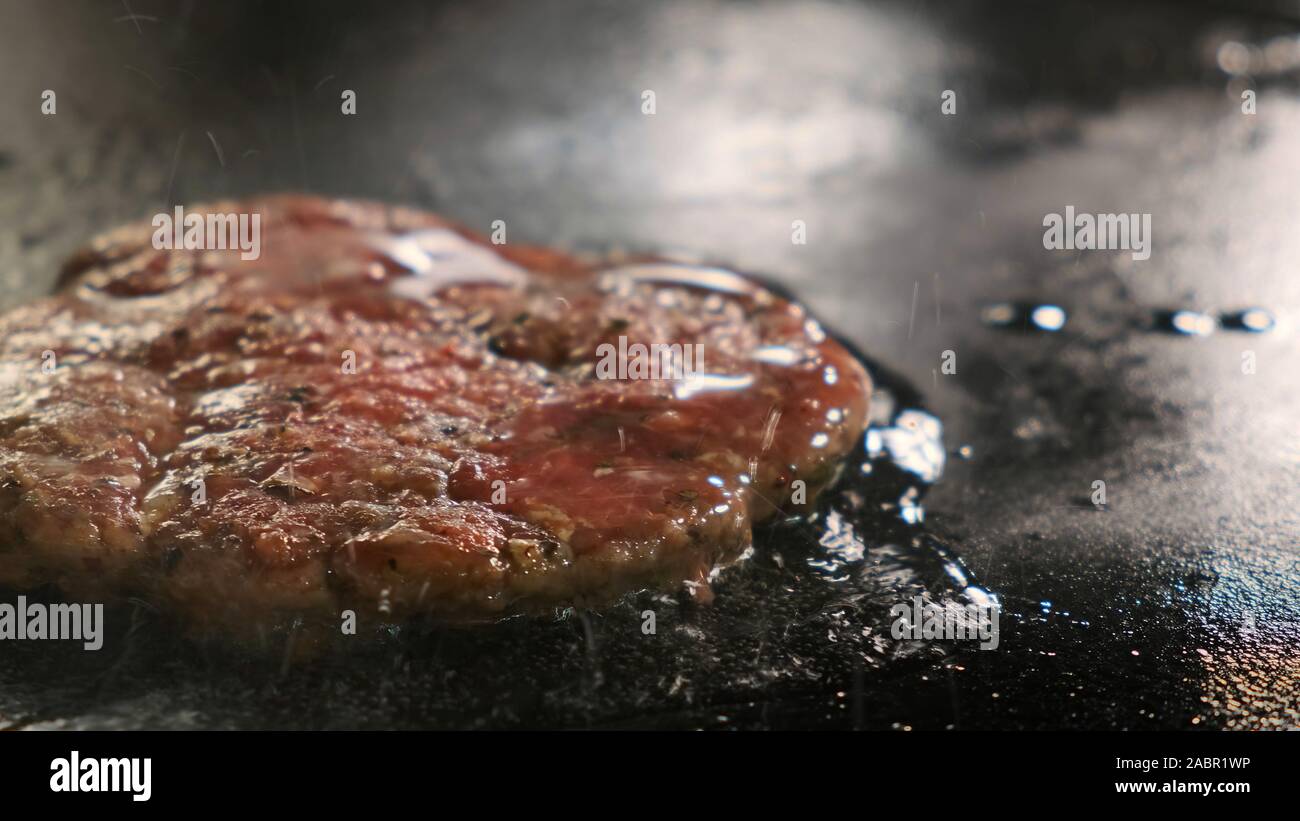 L'olio viene colata su una cotoletta. Extra di close-up di un cuoco di lubrificazione per un hamburger cotoletta Foto Stock