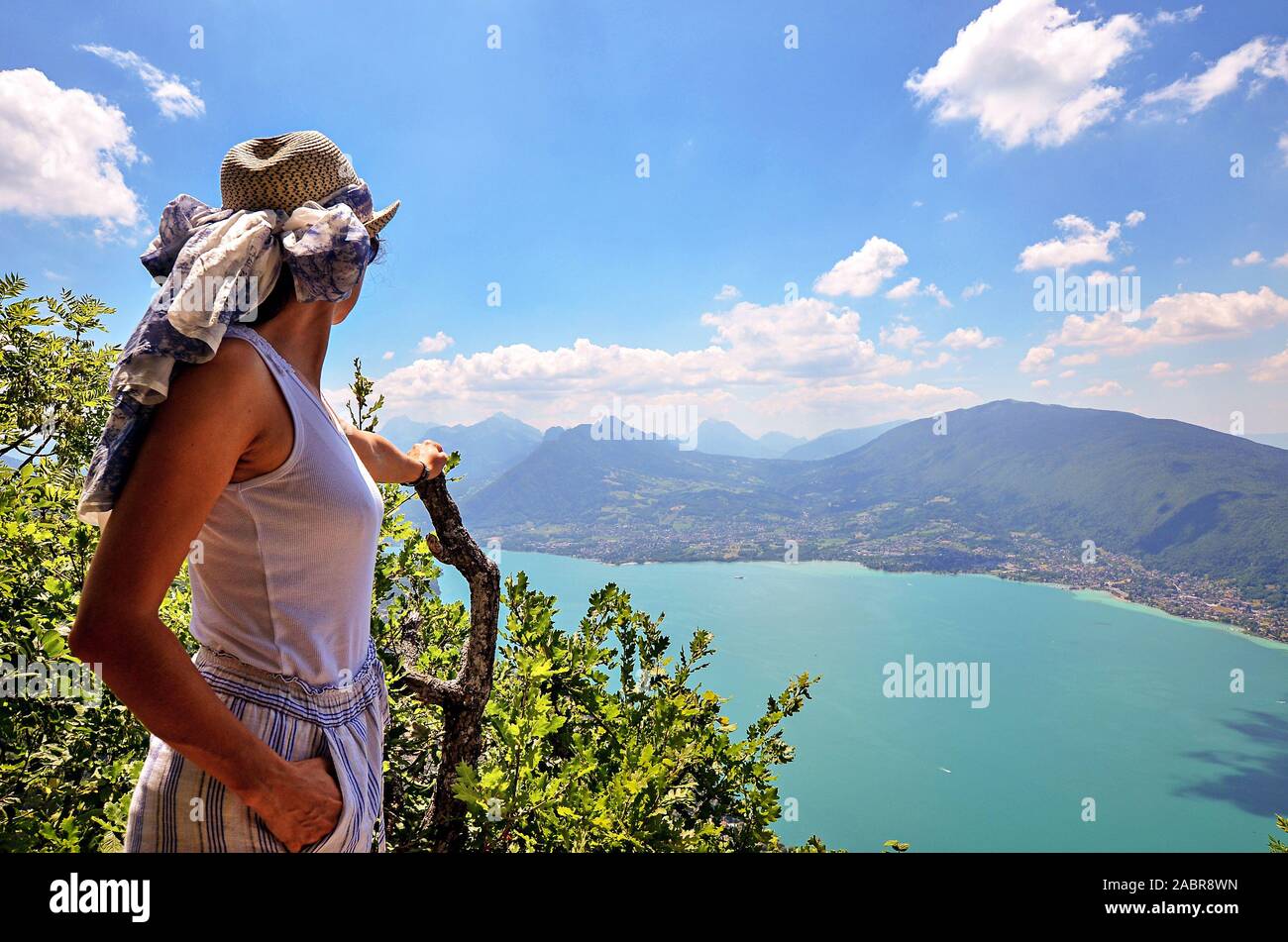 Una giovane donna felice indossando un cappello si ammira una vista panoramica sul lago di Annecy dal mont Veyrier al mont Baron escursionismo via, Francia Foto Stock