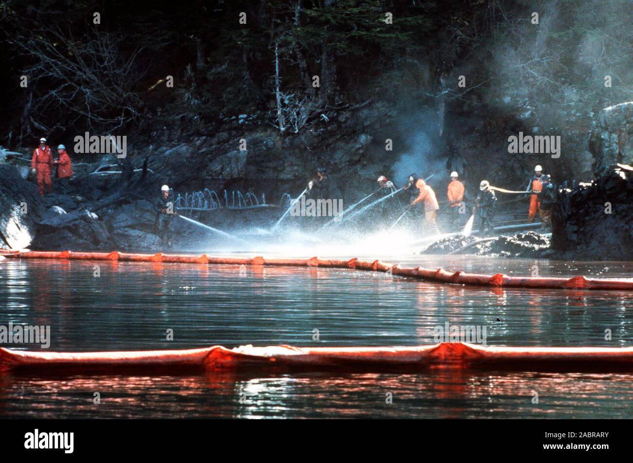 Prince William Sound, AK (Mar. 28)--lavoratori sbuffo di vapore rocce imbevuto di petrolio greggio dal perde petroliera Exxon Valdez. La Exxon Valdez si è arenata sulla Bligh Reef in Prince William Sound, Alaska, 23 marzo 1989 la fuoriuscita di 11 milioni di galloni di petrolio greggio che ha provocato la più grande marea nera nella storia degli Stati Uniti. Foto Stock