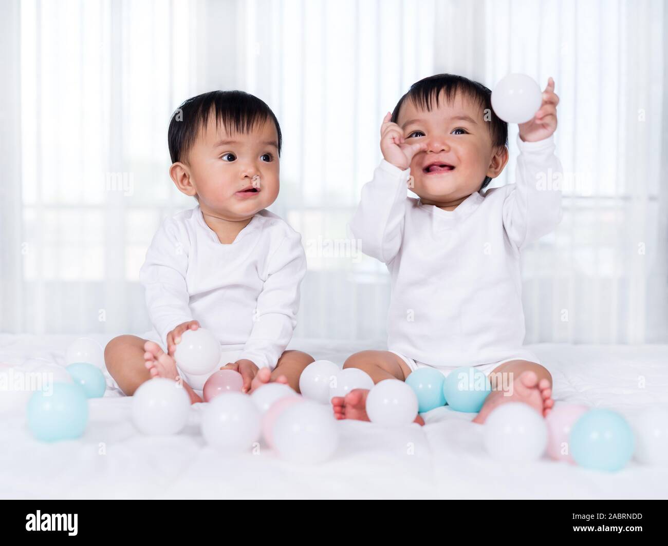 Allegro twin bambini giocare palla di colore su un letto Foto Stock