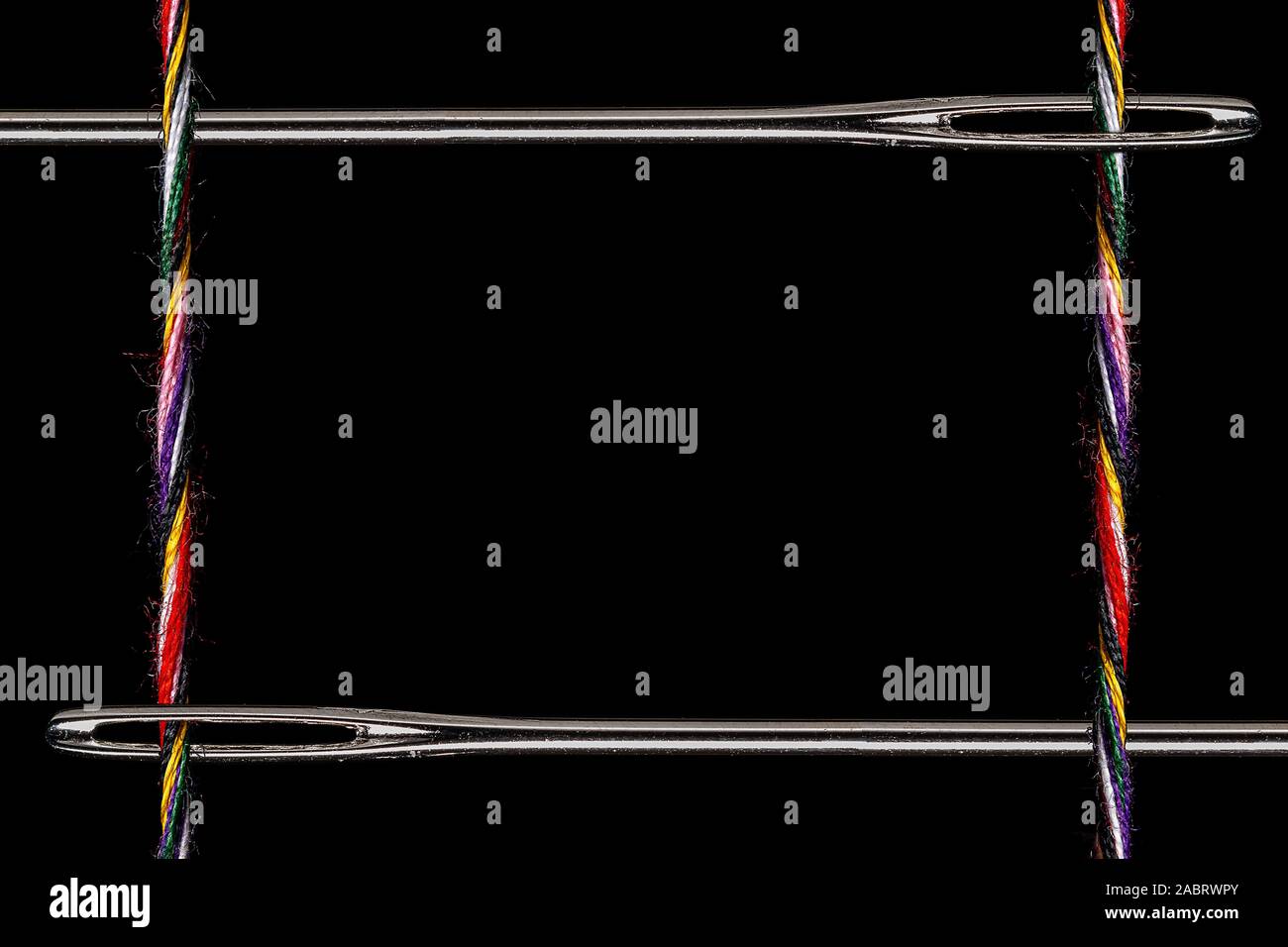 Un telaio di twisted multi-thread colorati e 2 aghi da cucire su uno sfondo nero. Vi è abbondanza di spazio per una copia o una foto nel centro con Foto Stock