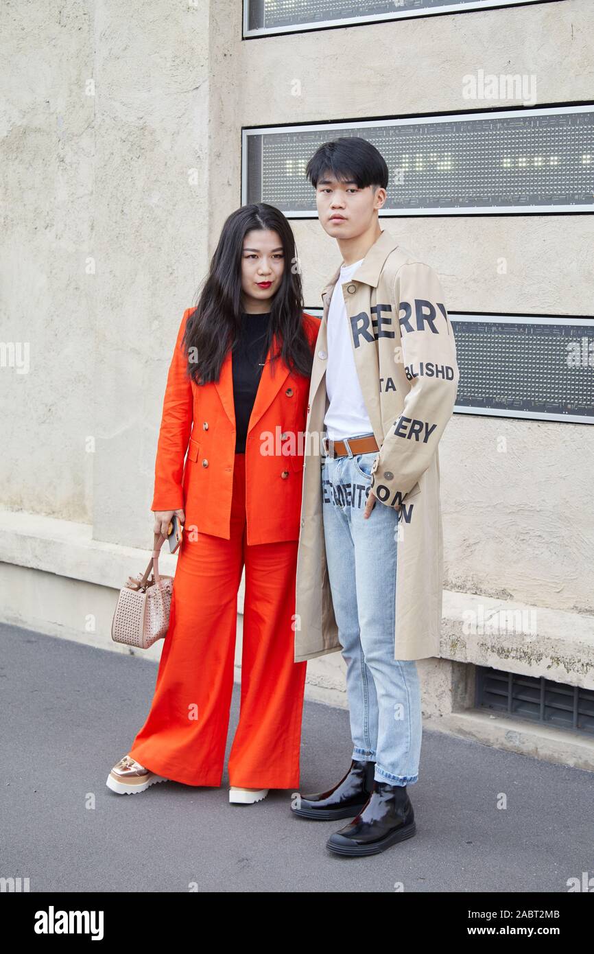 Milano, Italia - 18 settembre 2019: Donna con camicia arancione e pantaloni e uomo con Burberry trench coat prima di Prada sfilata di moda di Milano abbiamo Foto Stock