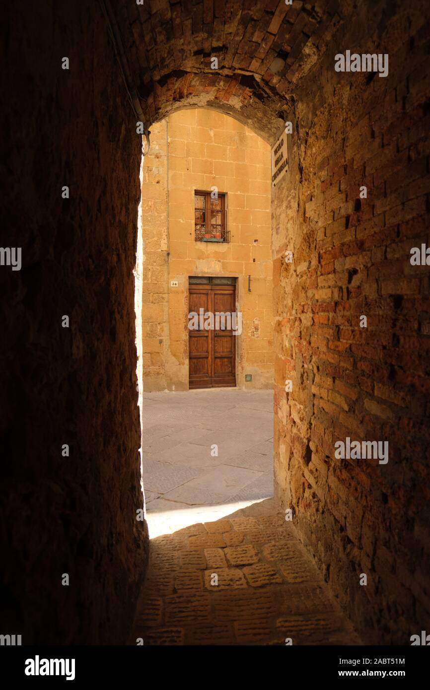 Uno stretto vicolo arcuata nel centro storico e architettura del sito patrimonio mondiale dell'UNESCO del Rinascimento Pienza cittadina collinare in Toscana Italia Foto Stock