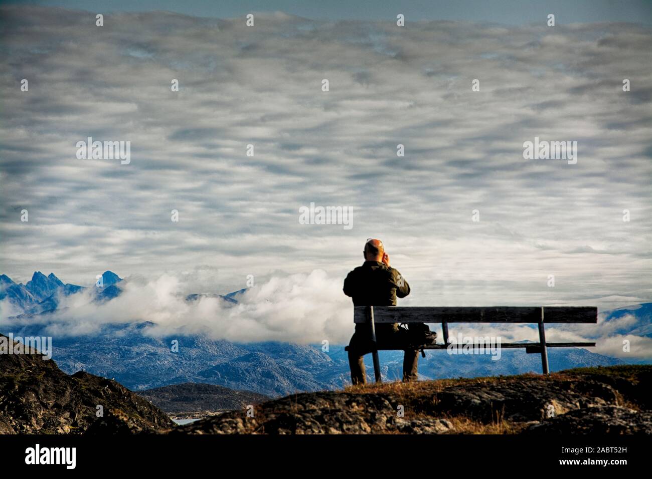 L'Europa, a sud-ovest della Groenlandia, Maniitsoq, uomo sul sedile accanto al cimitero Foto Stock