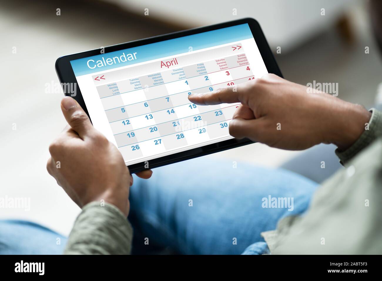 Immagine ritagliata di giovane che utilizza il calendario sulla tavoletta digitale in casa Foto Stock