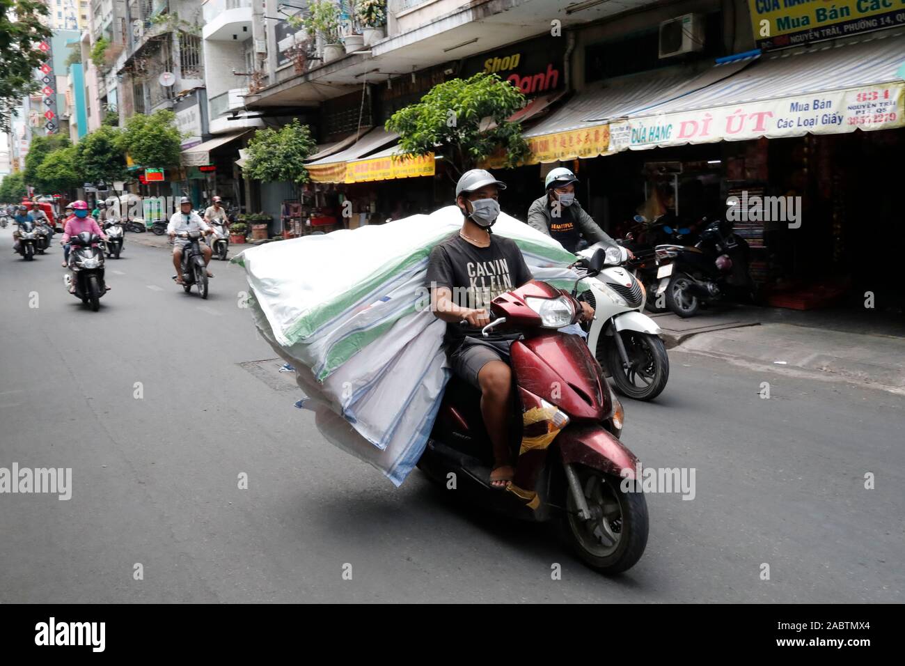 Scooter sono utilizzati per il trasporto di merci in luogo di vetture, spesso sovraccaricato e pericoloso. Ho Chi Minh City. Il Vietnam. Foto Stock