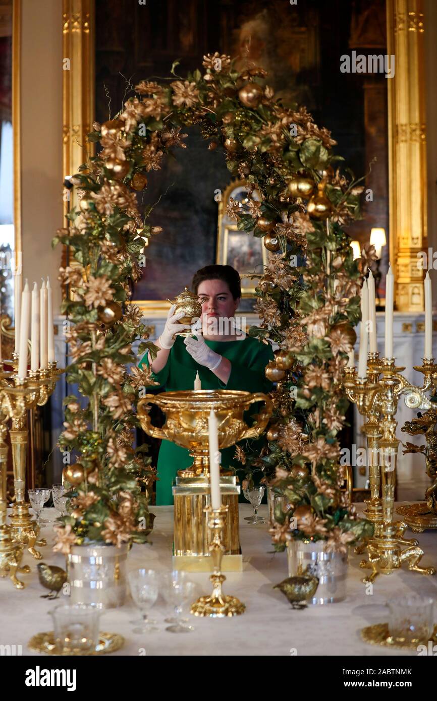 Un Royal Collection Trust membro del personale mette i tocchi di rifinitura per il gran servizio nello Stato sala da pranzo al Castello di Windsor, Berkshire. Foto Stock