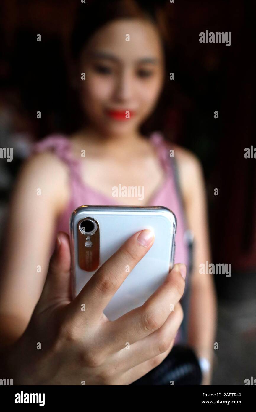 Donna asiatica tenendo selfie con smart phone. Hanoi. Il Vietnam. Foto Stock