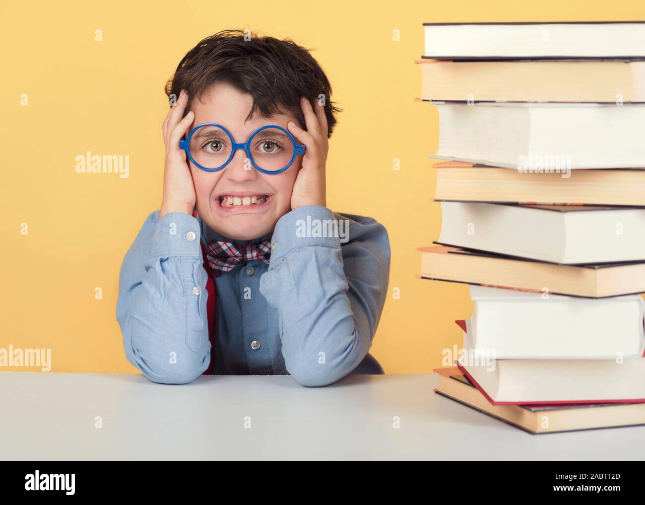 Bambino arrabbiato con libri su sfondo giallo Foto Stock