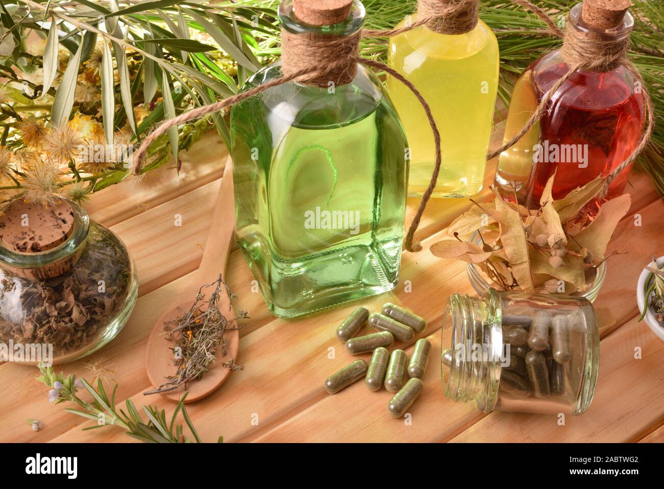 Capsule e bottiglie di essenza di medicina naturale con piante medicinali su un tavolo di legno. Vista in elevazione. Composizione orizzontale. Foto Stock
