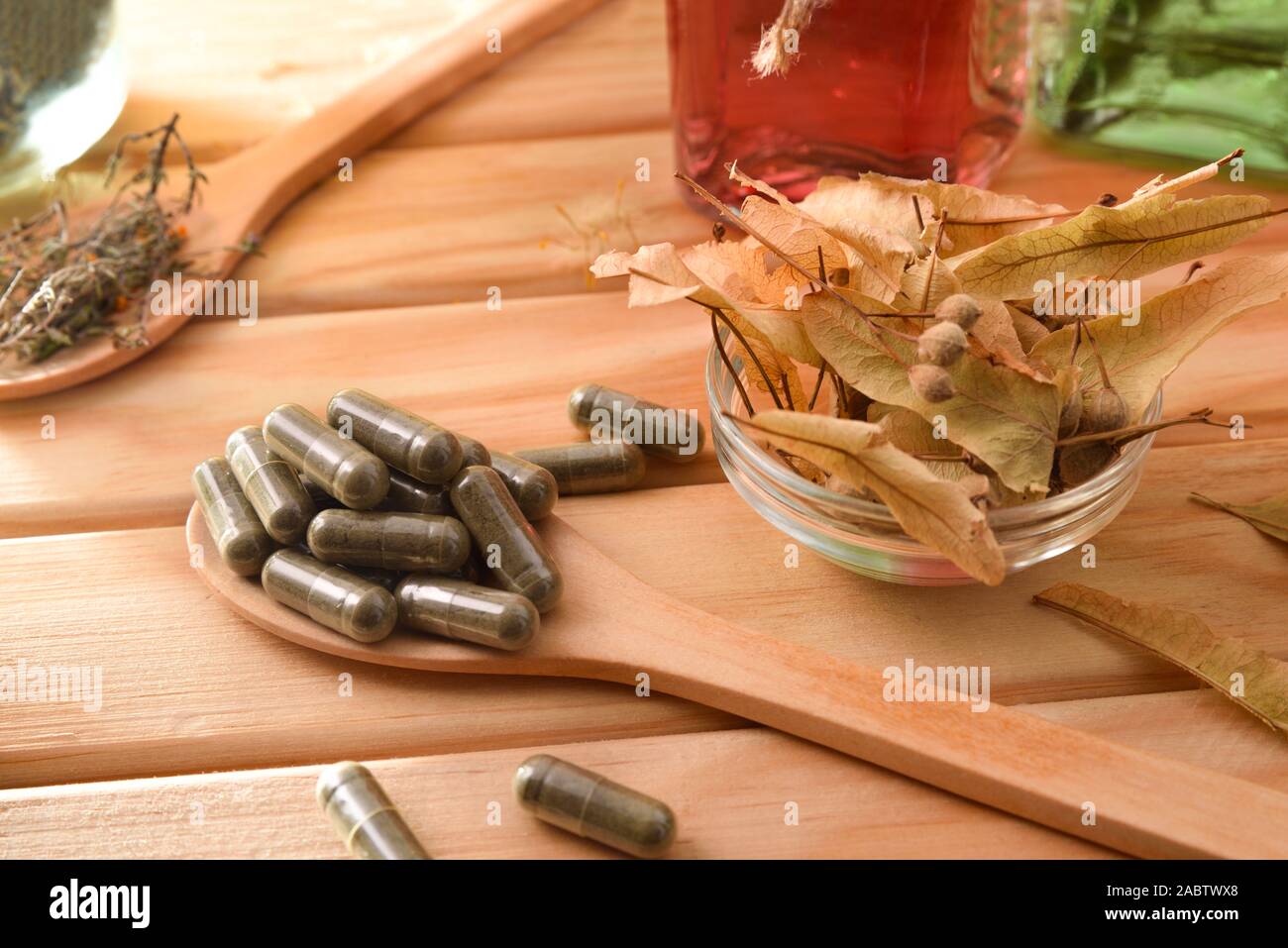 Capsule e bottiglie di essenza di medicina naturale con piante medicinali su un tavolo di legno. Vista in elevazione. Composizione orizzontale. Foto Stock