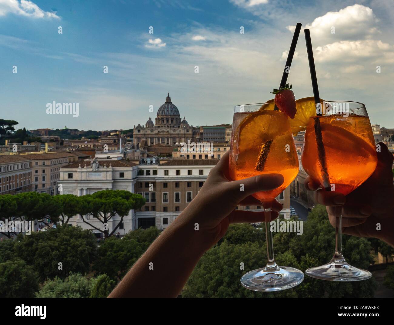 Un giovane è in possesso di bicchieri di Aperol nel bar all'interno del Castello di Sant'Angelo. Bicchieri di Aperol e la basilica di San Pietro sullo sfondo. Foto Stock