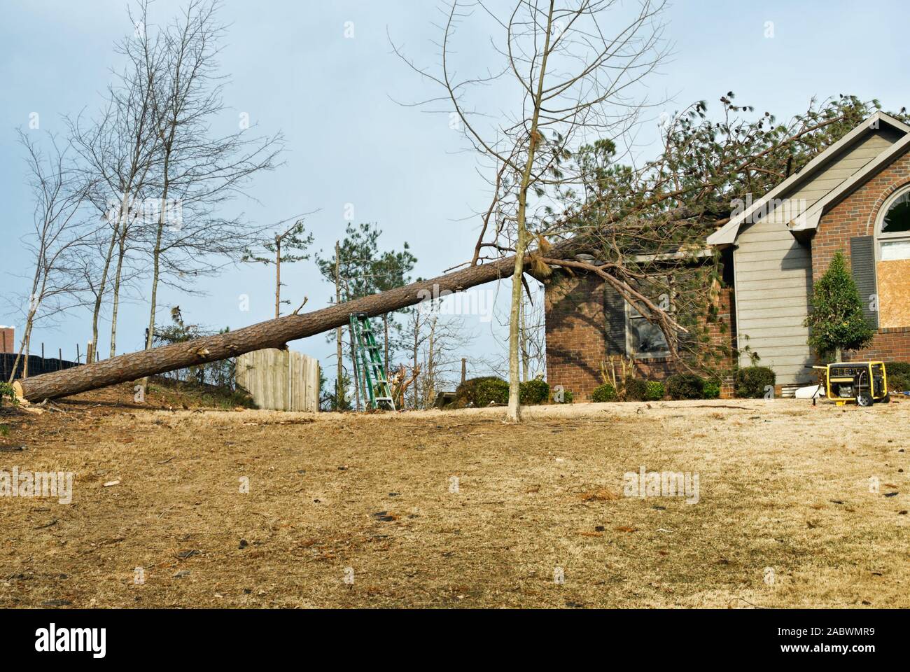 Tornado casa danneggiata con un caduto albero di pino sul tetto a seguito di una primavera in caso di calamità naturali. Foto Stock