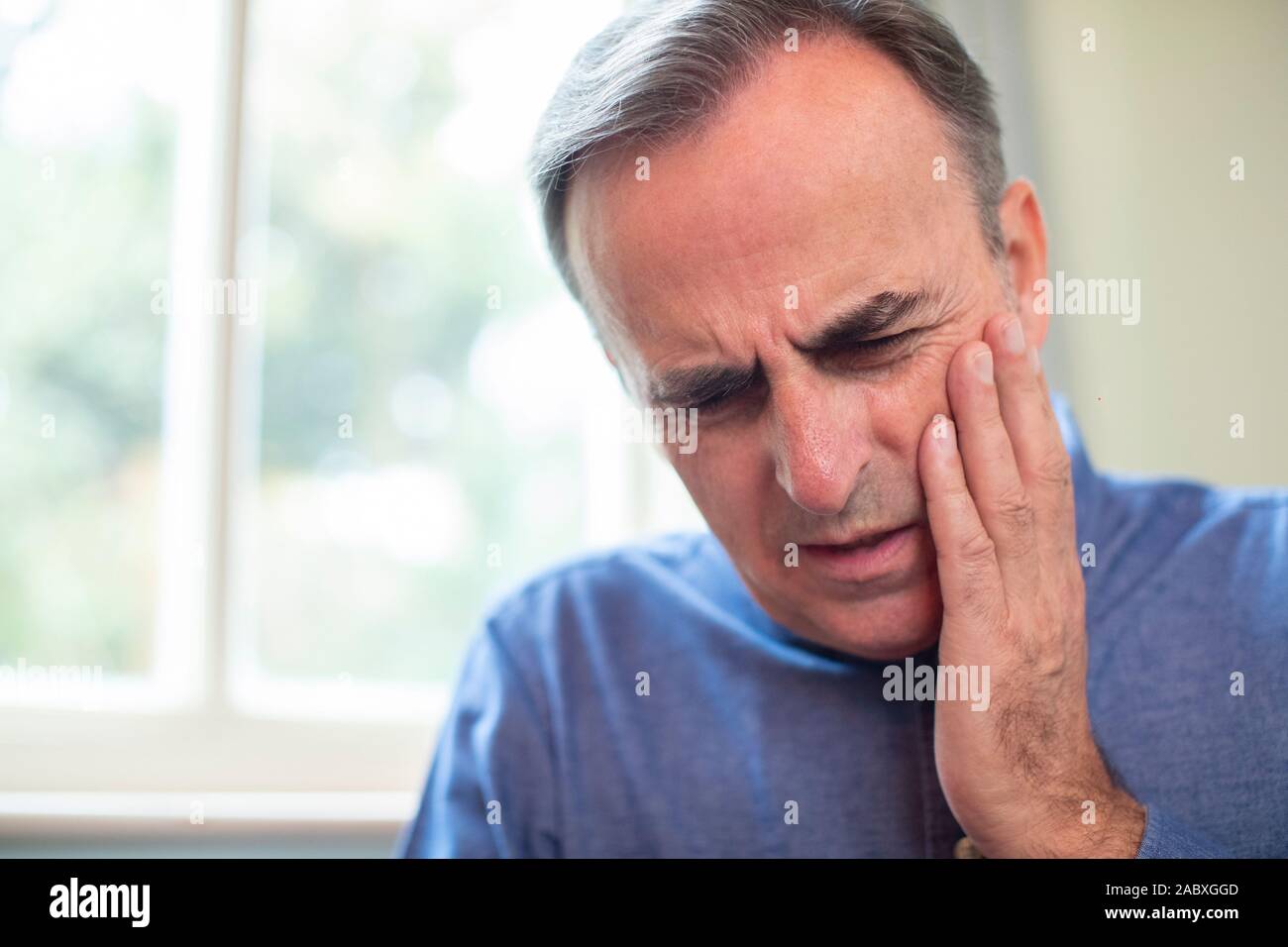 Uomo maturo la sofferenza con il mal di denti e sfregamento dente doloroso Foto Stock