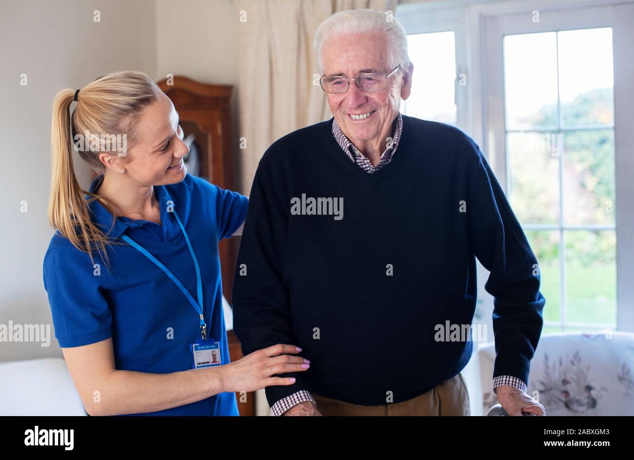 Senior Uomo con telaio a piedi essendo aiutato dal lavoratore di cura Foto Stock