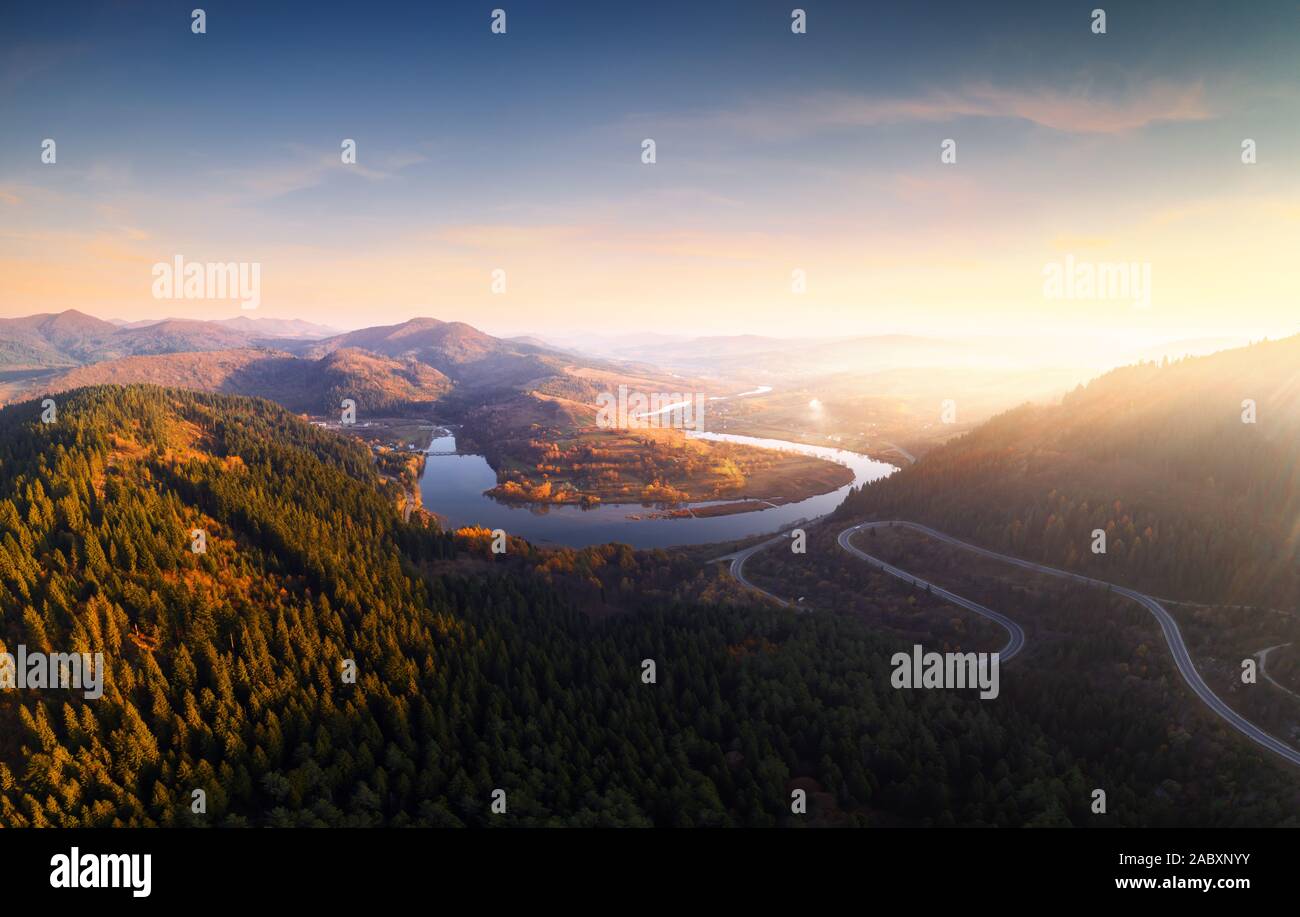 Antenna fuco vista sulle montagne di autunno con la strada di montagna serpentina, fiume e foresta. Fotografia di paesaggi Foto Stock