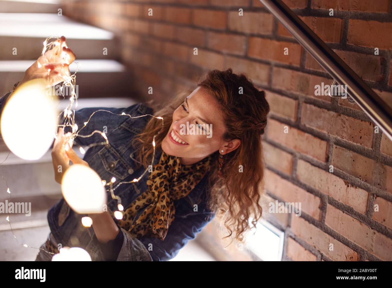 20s redhead donna caucasica a giocare con le luci fairy all'aperto Foto Stock