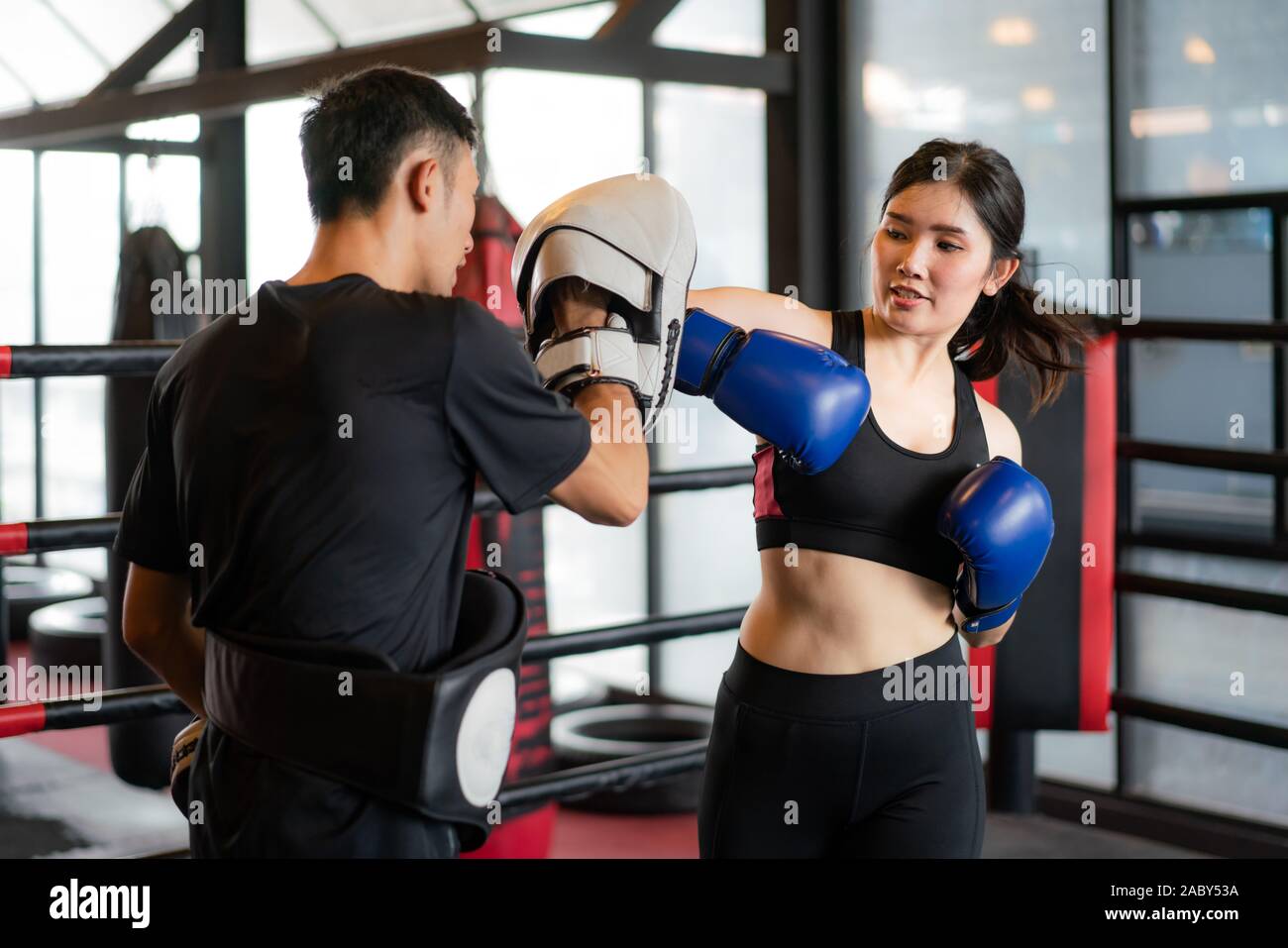 Giovane donna asiatica boxer colpisce con un gomito al trainer professionale nella boxe studuim in background in palestra per il fitness. Montare sportivo per una sana vita Foto Stock