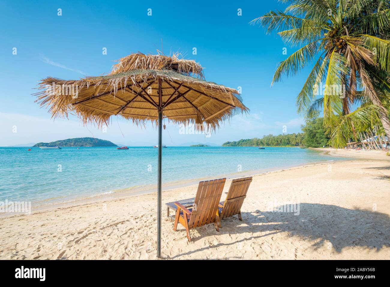 Sedie a sdraio e ombrellone in estate isola con acqua chiara mare e onda con barca veloce in background in Phuket, Tailandia. Estate, Viaggi, vacanze a Foto Stock