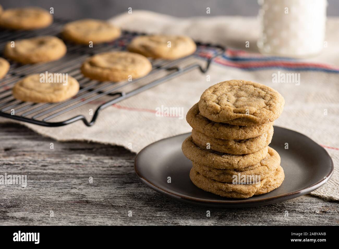 Biscotti al burro di arachidi appena sfornati con un bicchiere di latte ghiacciato. Servito un tavolo rustico in legno. Foto Stock