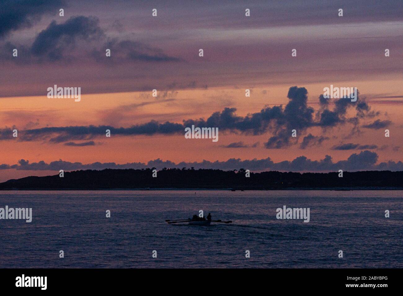 Un pilota della Cornovaglia gig barca essendo remato tra le isole Scilly al tramonto Foto Stock