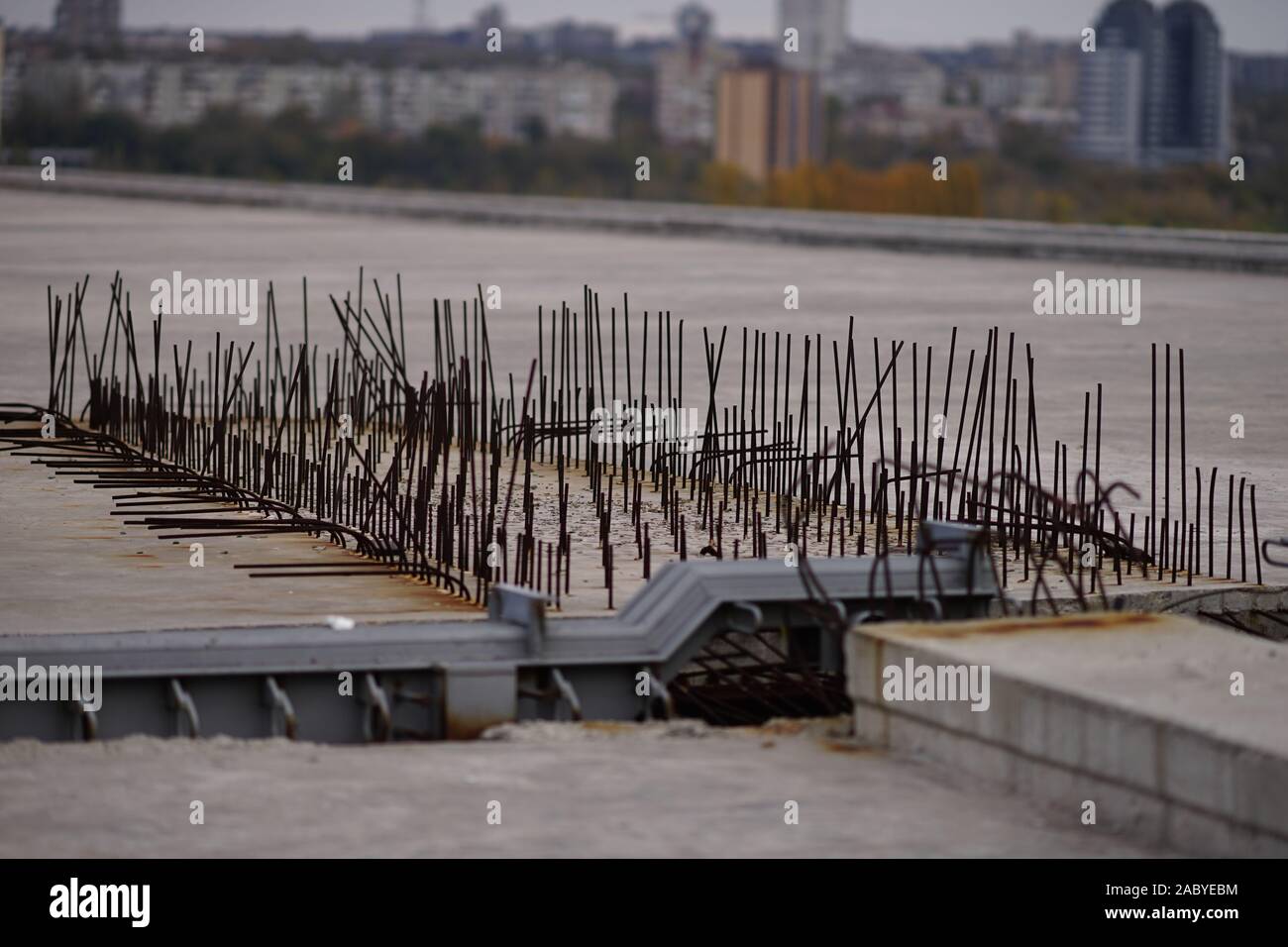 Barre di rinforzo in una struttura in cemento armato di un ponte in costruzione contro lo sfondo della città Foto Stock