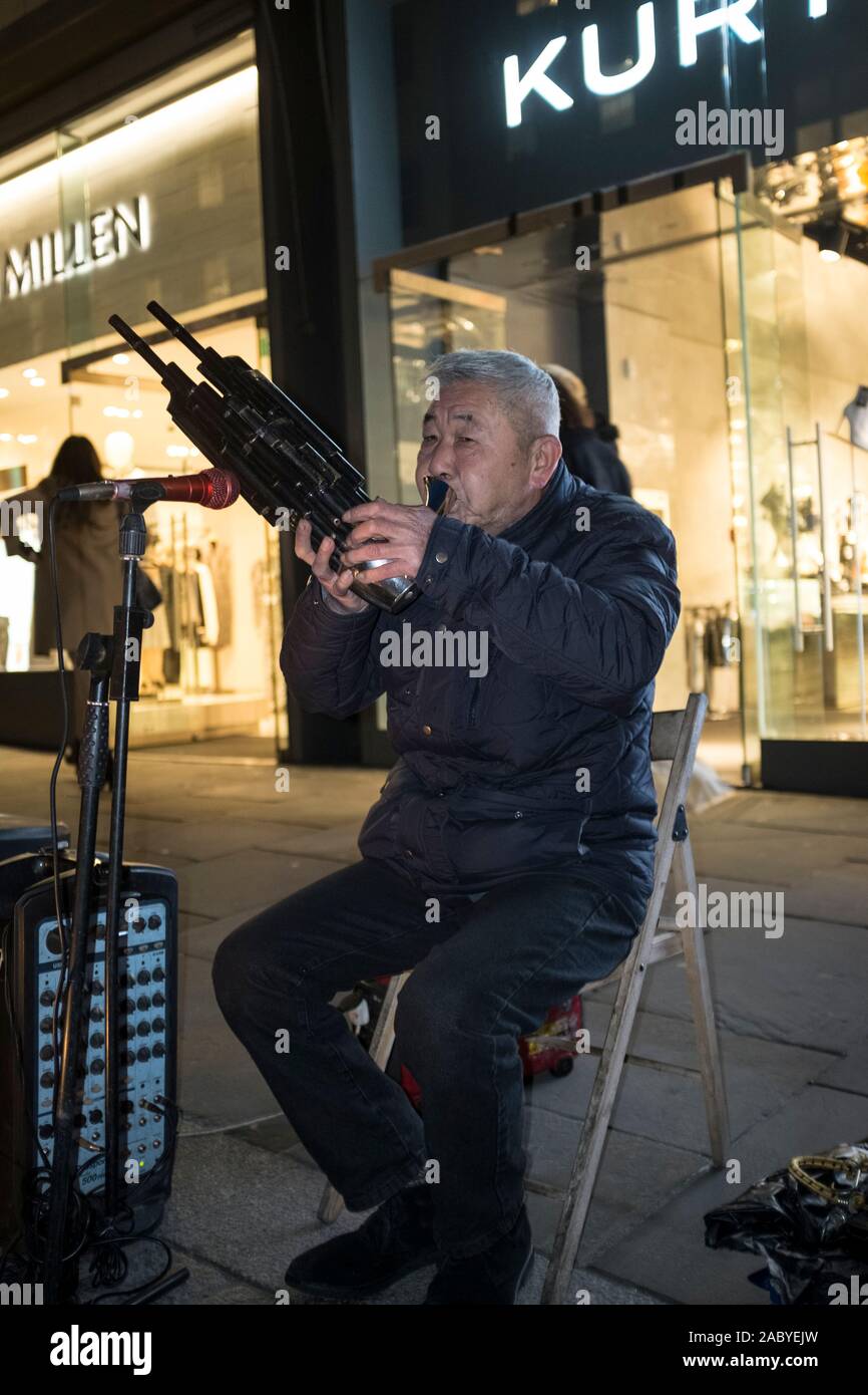 Musicista di strada (Cinese?) riproduzione sheng, uno dei più antichi reeded cinese di strumenti a fiato. Si tratta di un multi-reed armonica a bocca che consistono di numerose Foto Stock