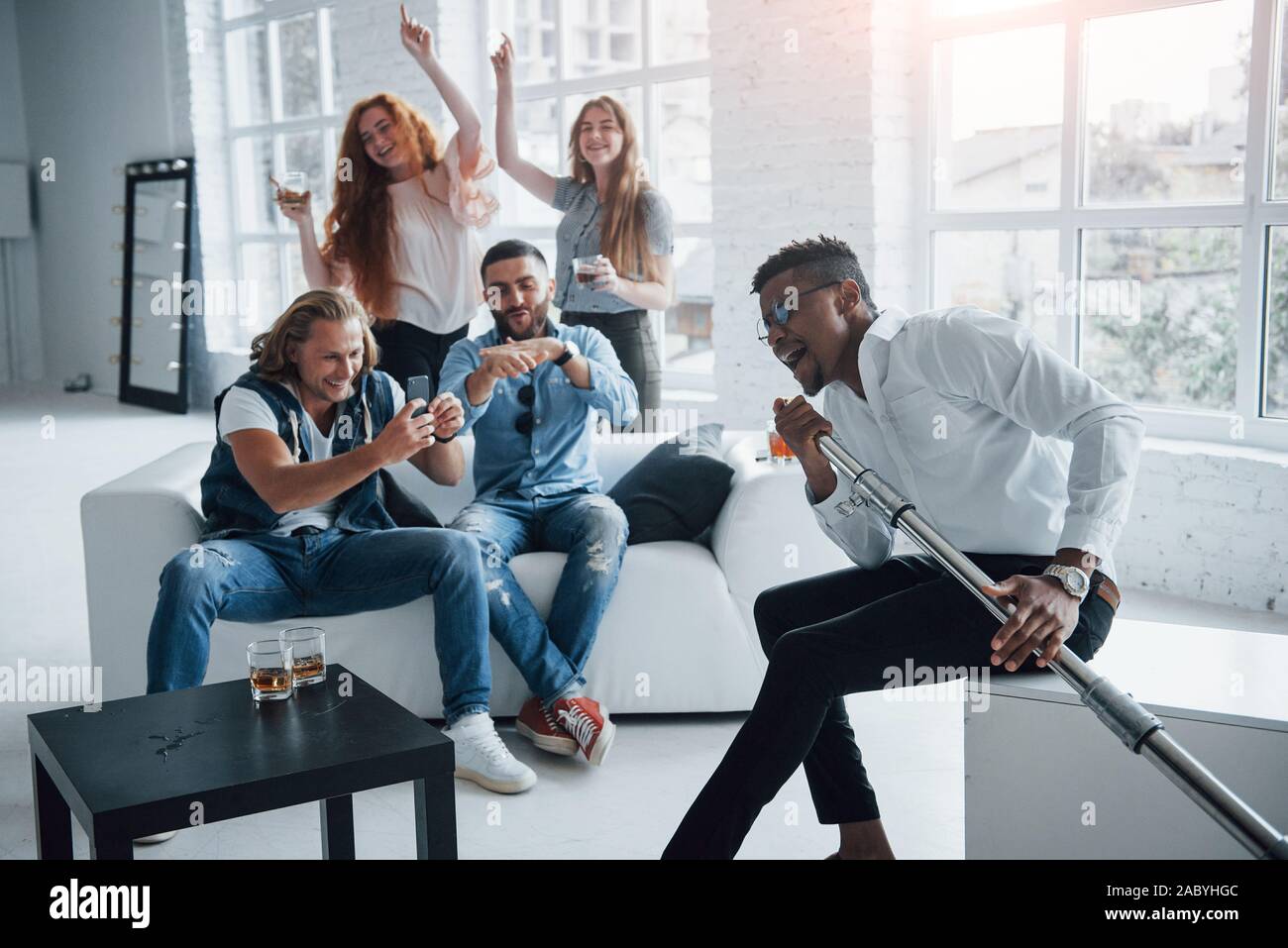 Awesome afro american guy nella parte anteriore delle persone inizia la folla. Gli amici decide di rilassarsi cantando i loro brani preferiti Foto Stock