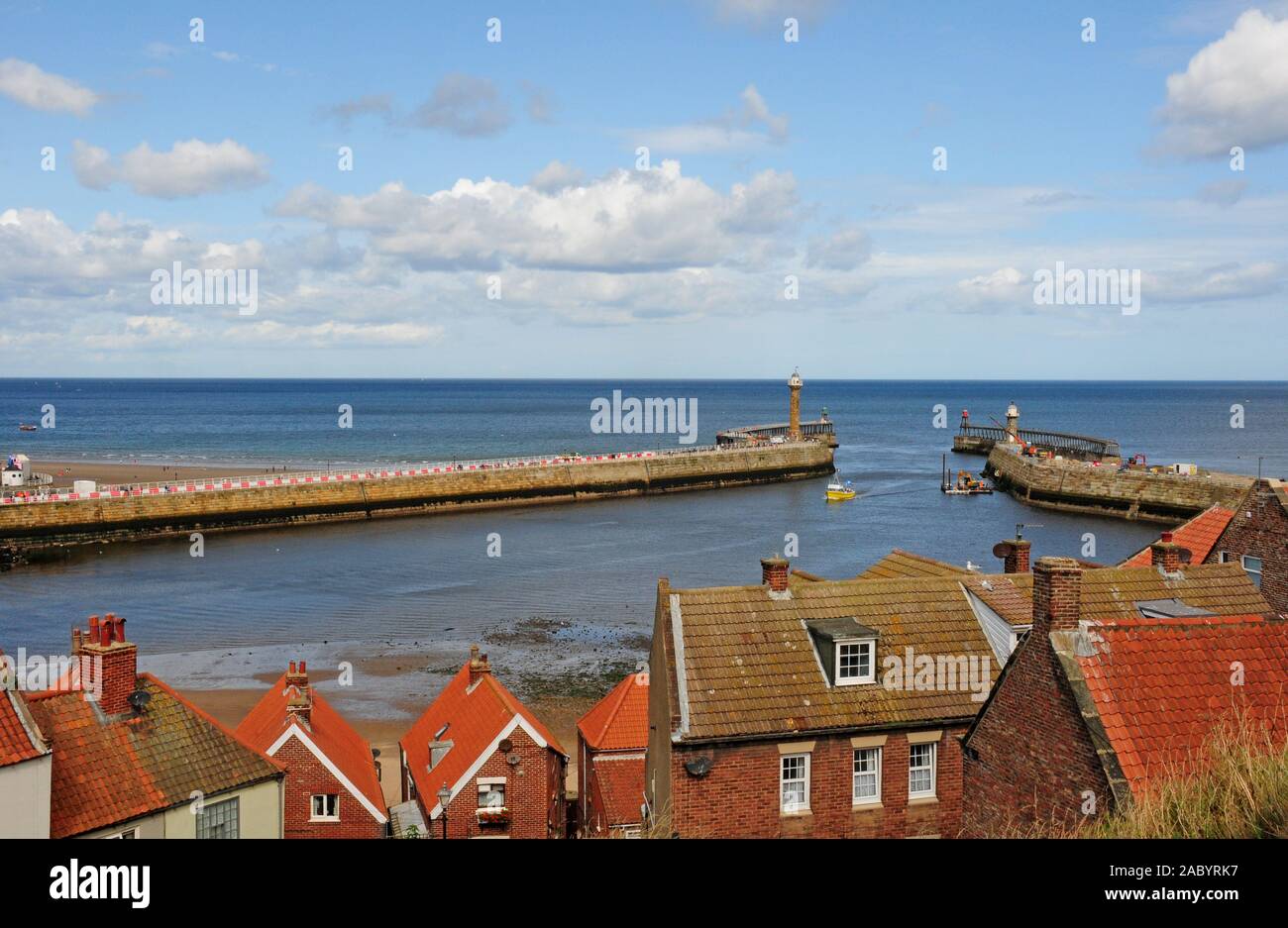 Tetti di Whitby. Fiume Esk estuario con la bassa marea. Imbarcazione da diporto in arrivo al Porto di Whitby. Foto Stock