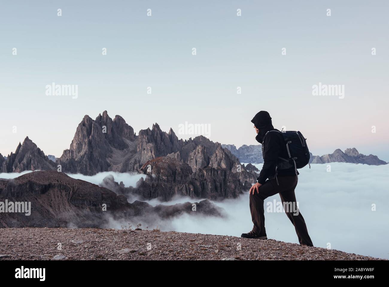 Adulto tourist camminano sul bordo della collina e guardare e grandi montagne sullo sfondo Foto Stock